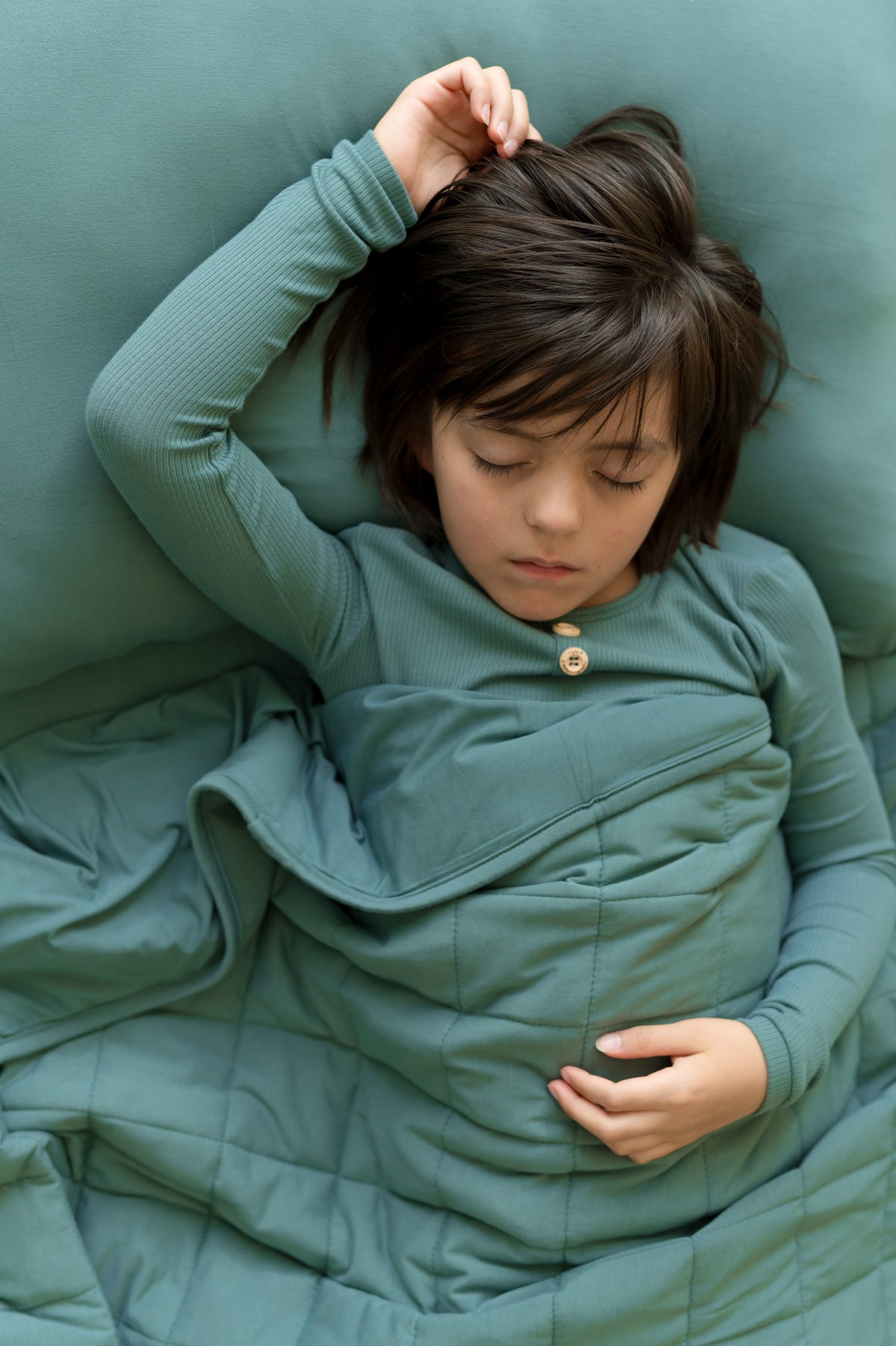 Boy sleeping on Standard Pillowcase in Pine over a bed with pine sheet and wearing pine shirt covered with pine blanket
