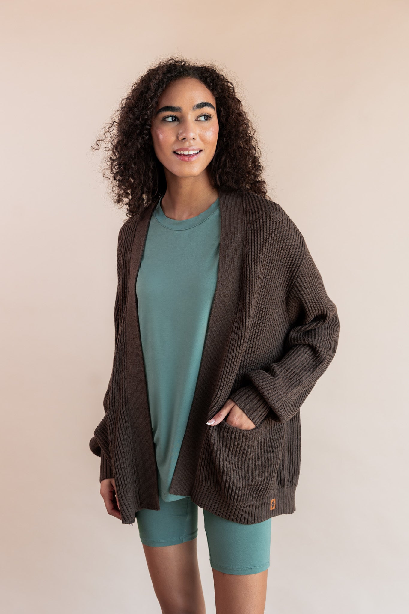 Model wearing Women’s Biker Short Set in Pine with Chunky Knit Oversized Cardigan in Espresso