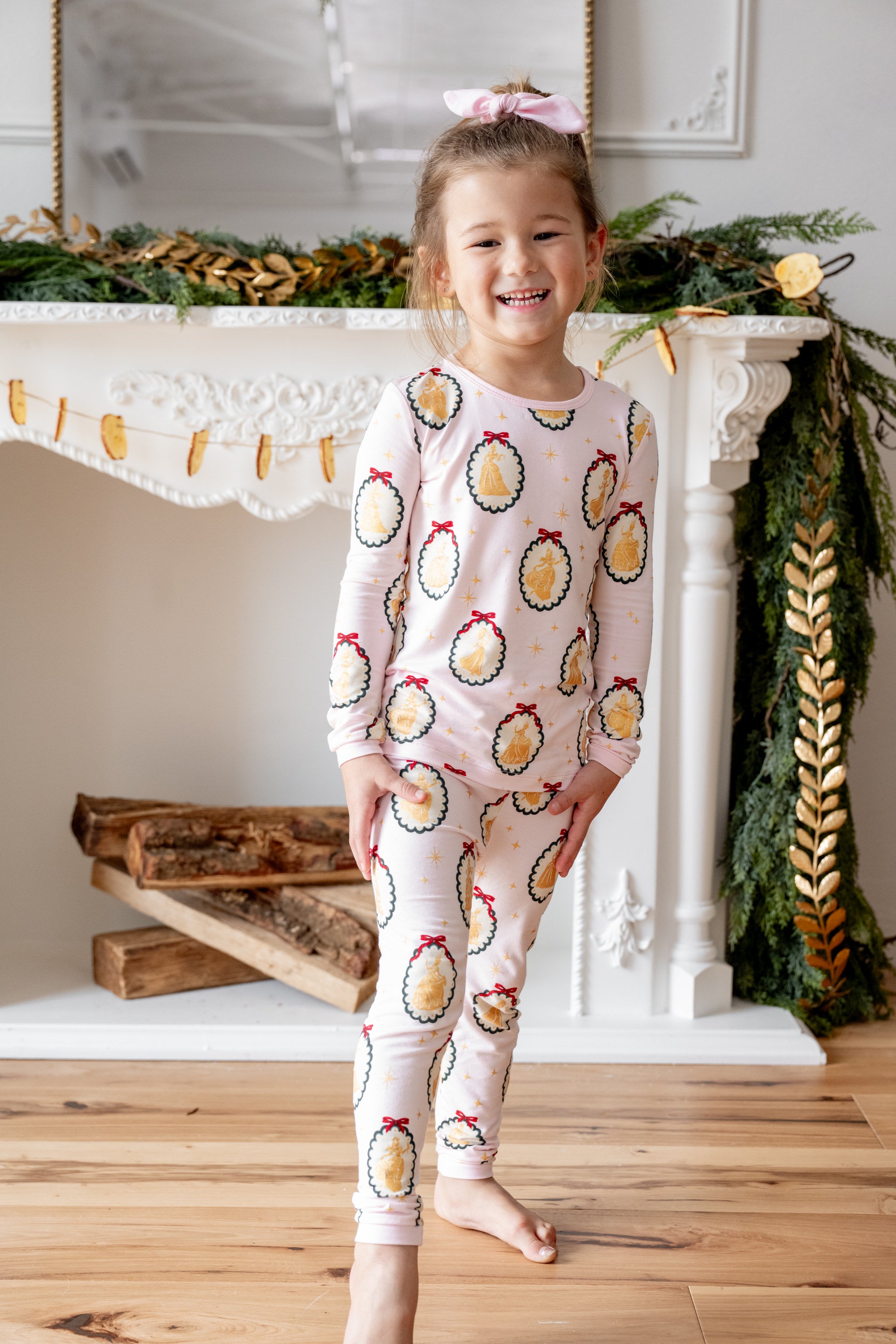 Girl wearing Long Sleeve Pajamas in Princess Holiday Portraits print smiling in front of fire place