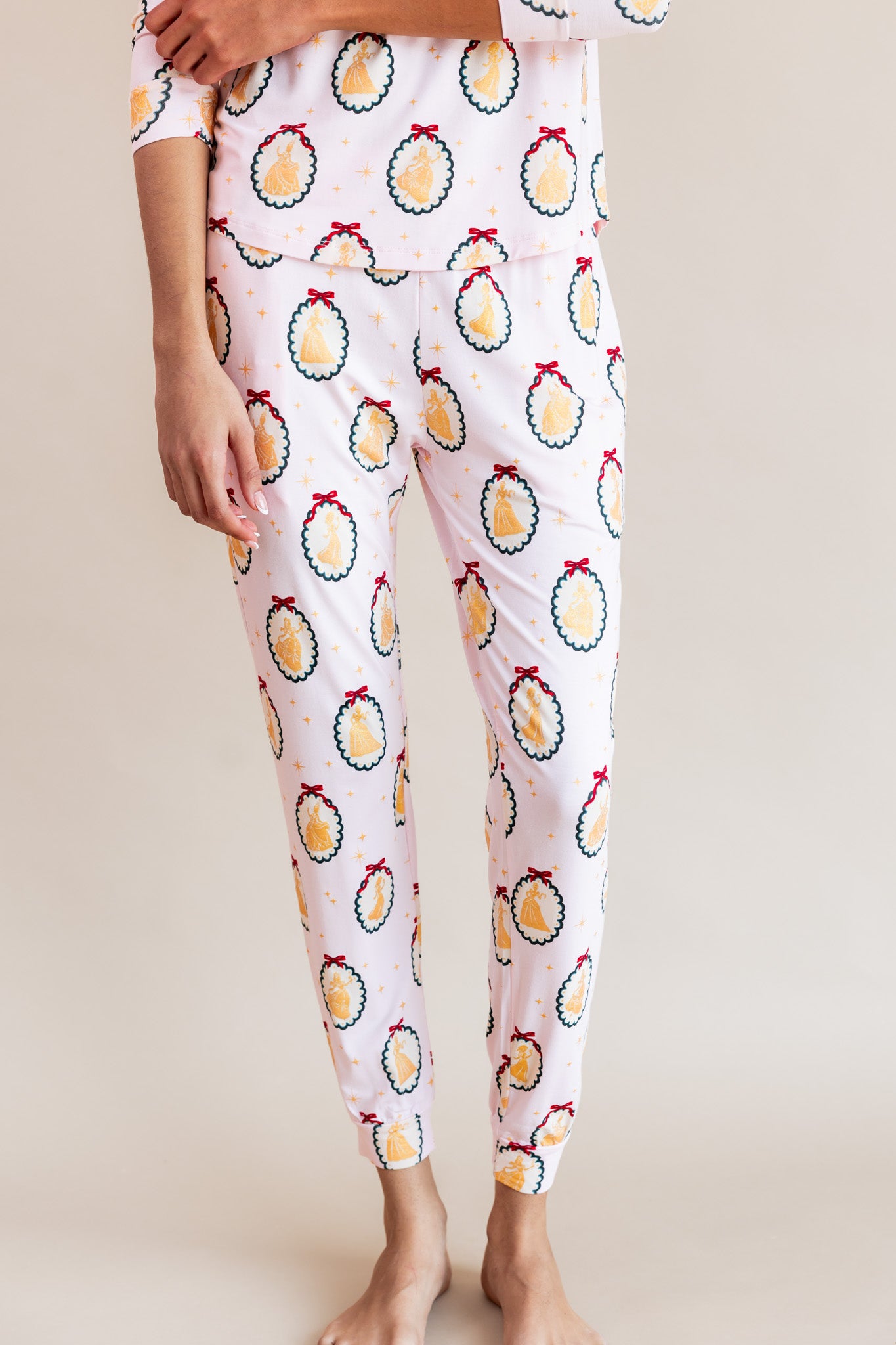 Close up of Women's Jogger Pajama in Princess Holiday Portraits print on a beige background