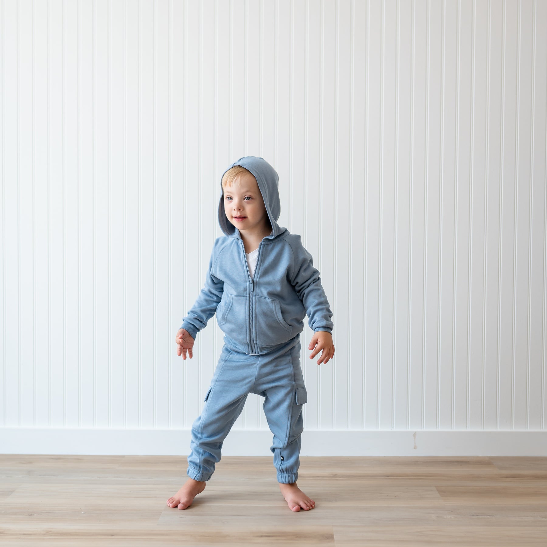 Young boy standing wearing the Fleece Cargo Pants in Slate with matching fleece zip hoodie with the hood up 