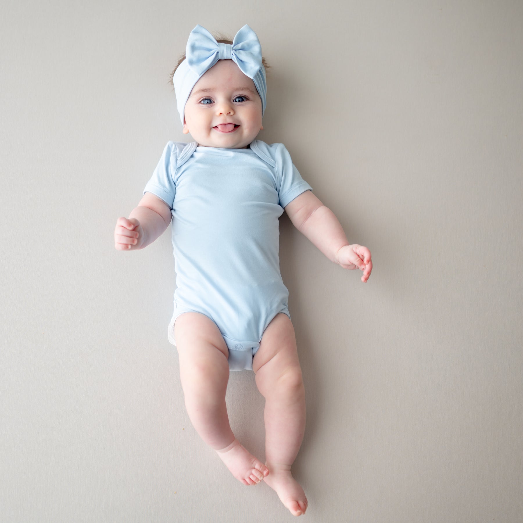 Baby wearing light blue short sleeve bodysuit and bow