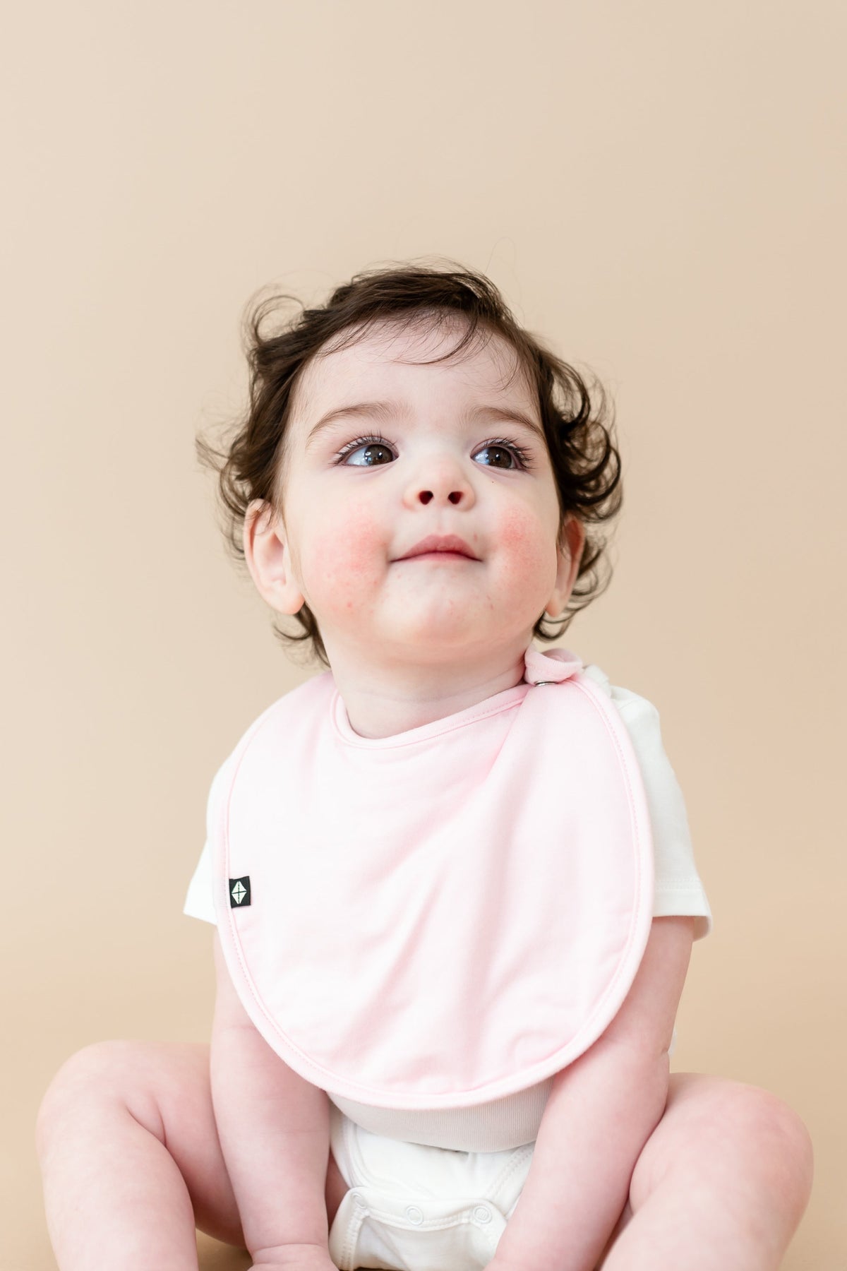 Baby wearing Cushy Bib in Sakura Pink