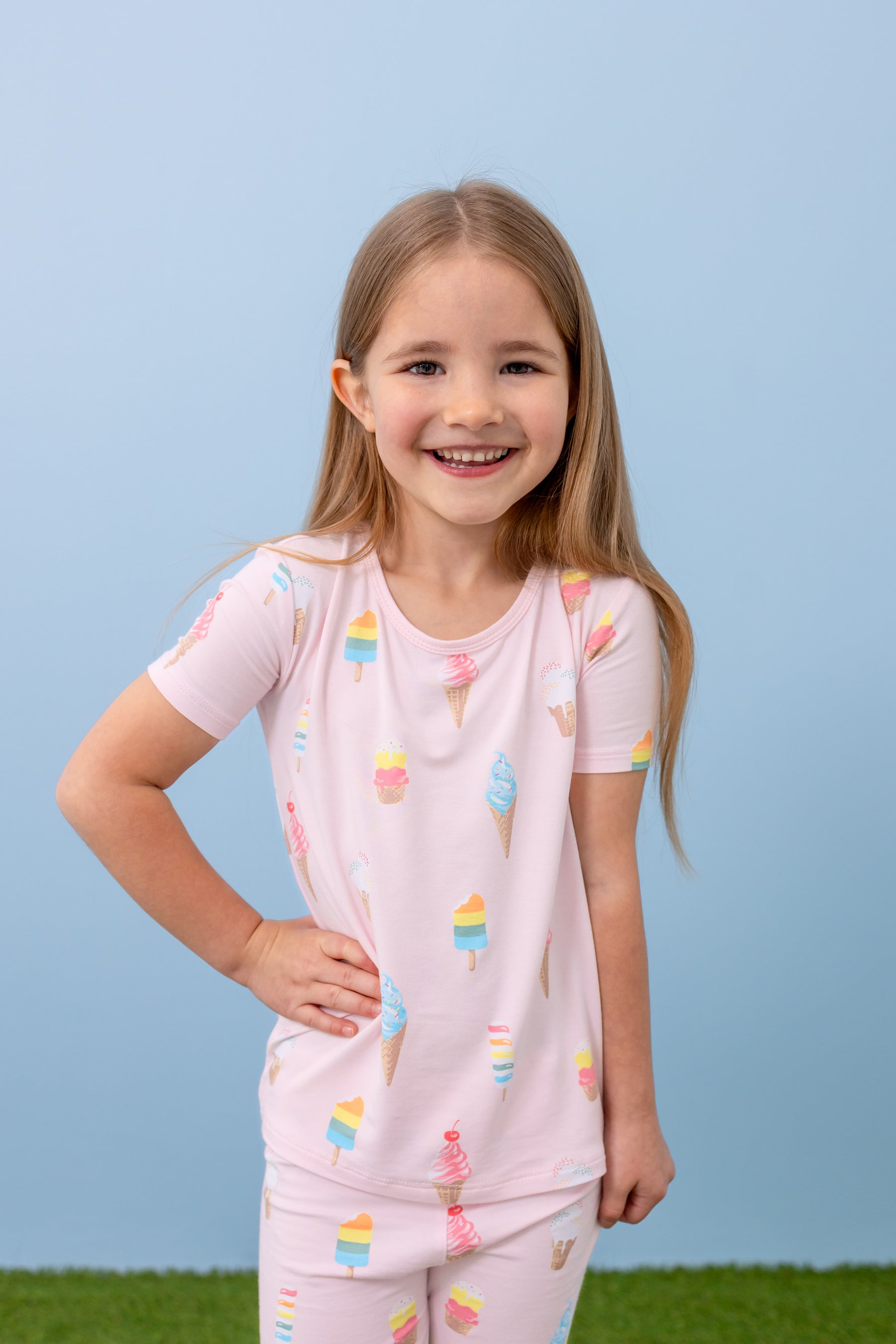 Child posing in short sleeve pajama set in Sakura Ice Cream print on a blue background