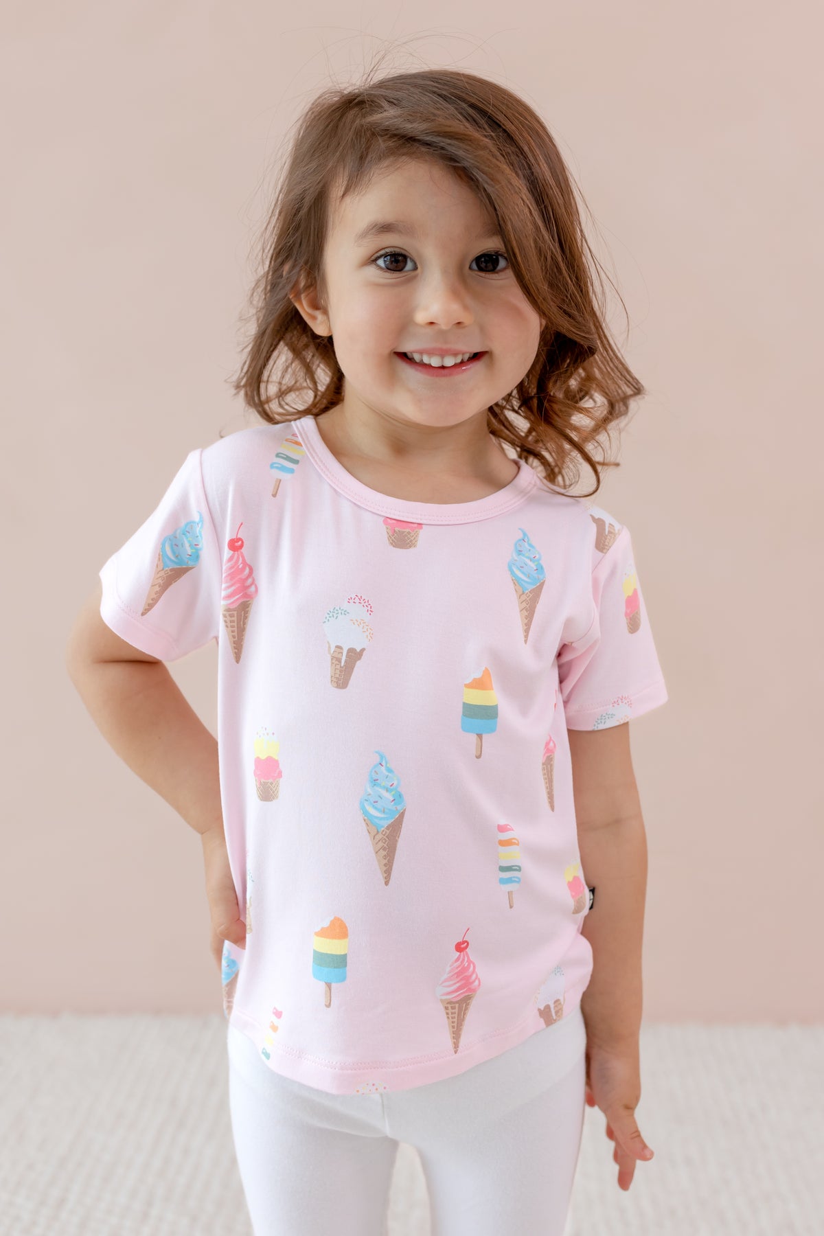 Child wearing Toddler Basic Tee in Sakura Ice Cream print over white leggings on a beige background