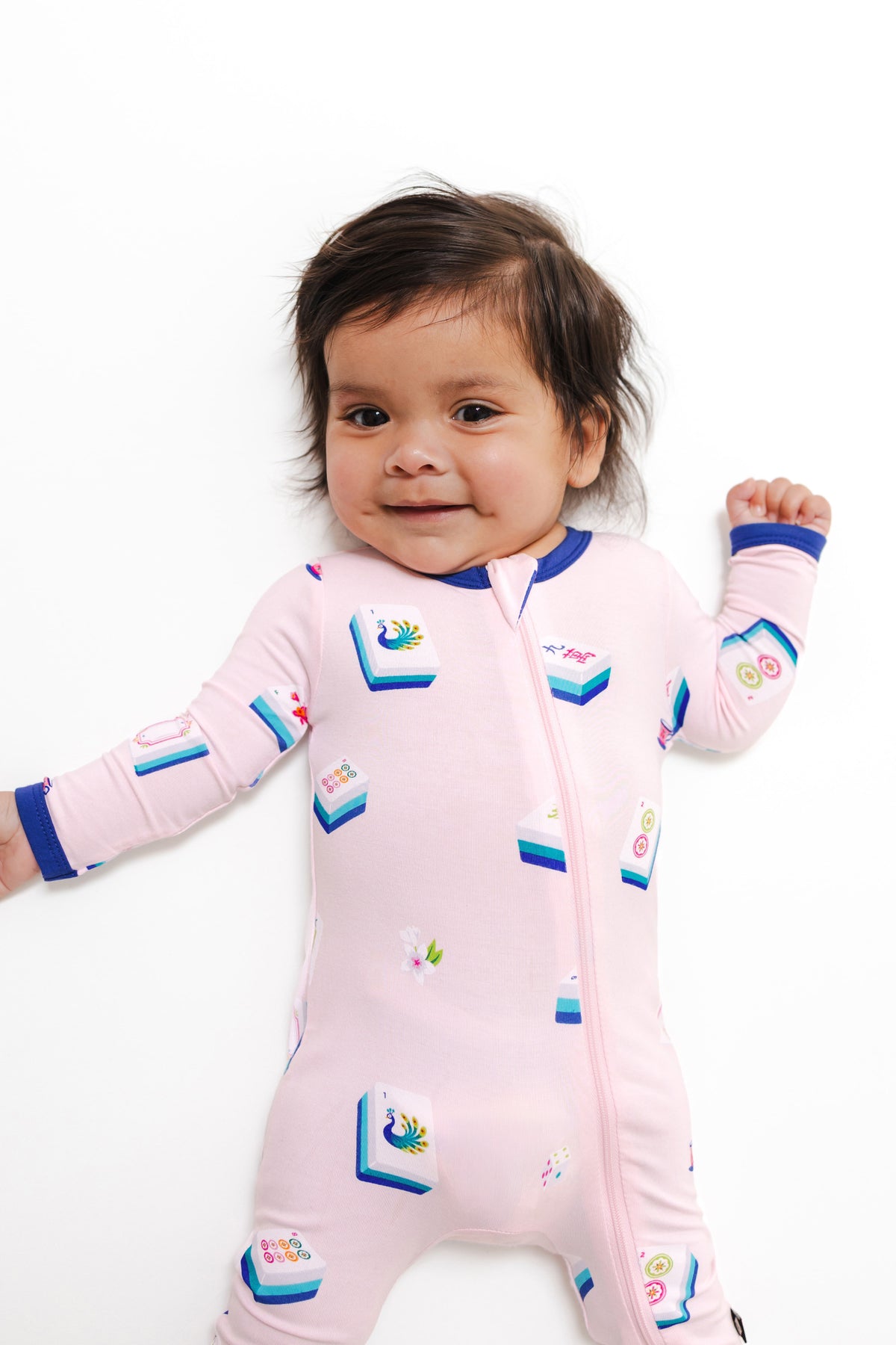 close up of Baby wearing Zippered Romper in Sakura Mahjong print on a white background