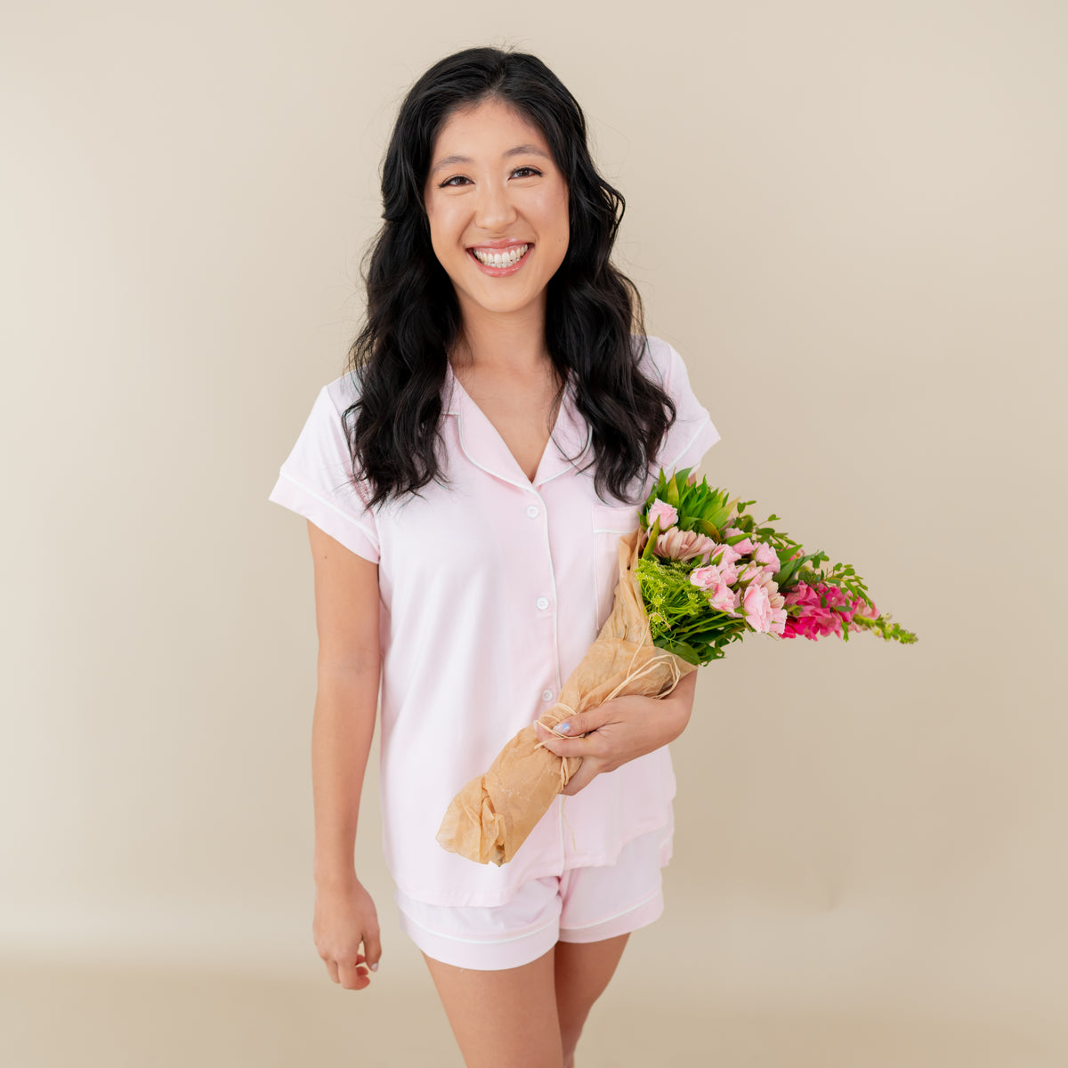 Woman modeling Women’s Short Sleeve Pajama Set in Sakura with Cloud Trim holding a bouquet 