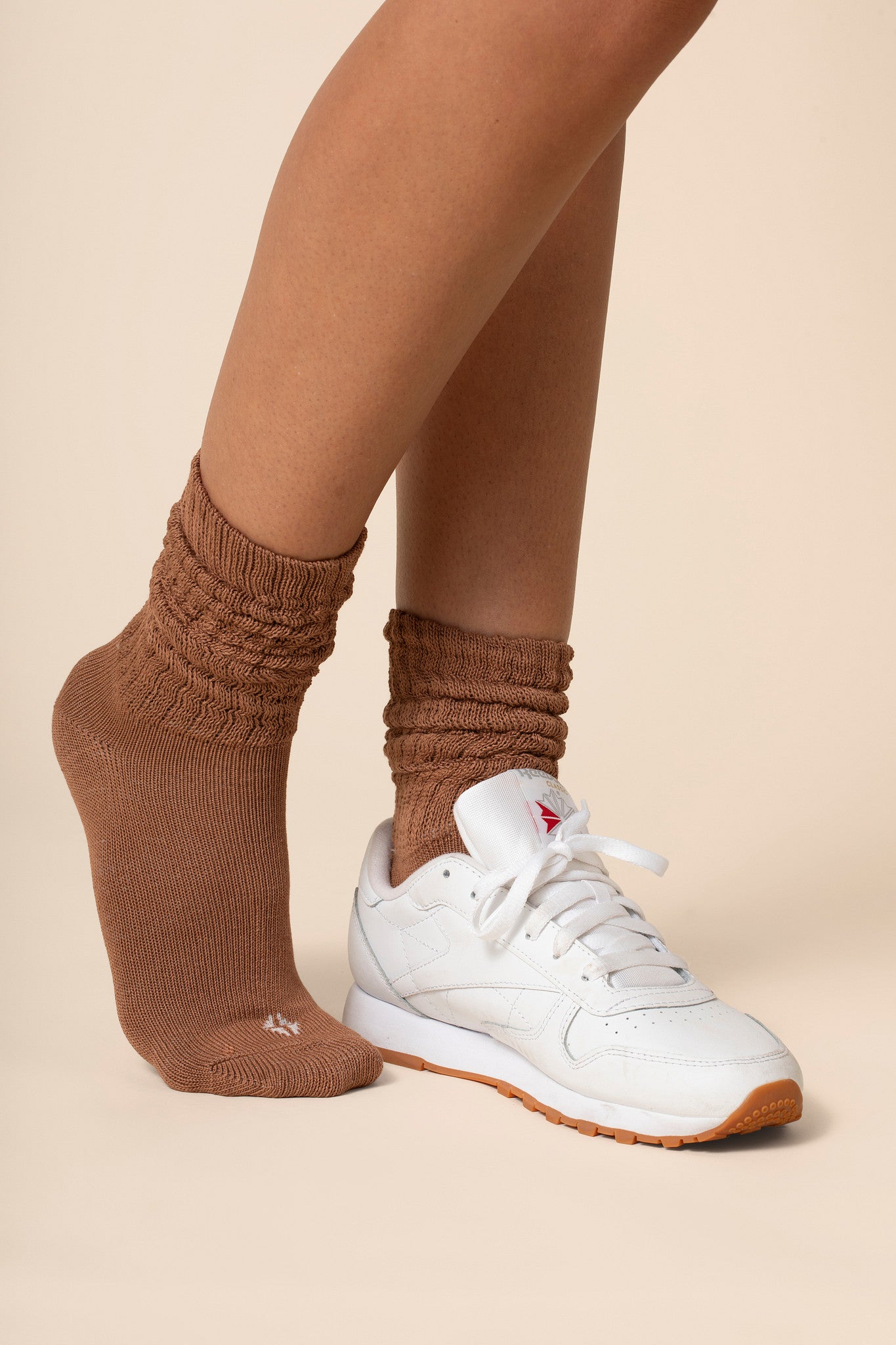 Brown socks worn with a white sneaker on a beige background