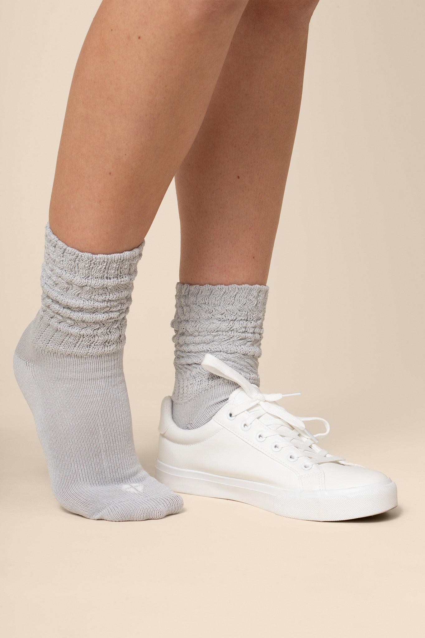 Gray socks worn with white sneakers on a beige background