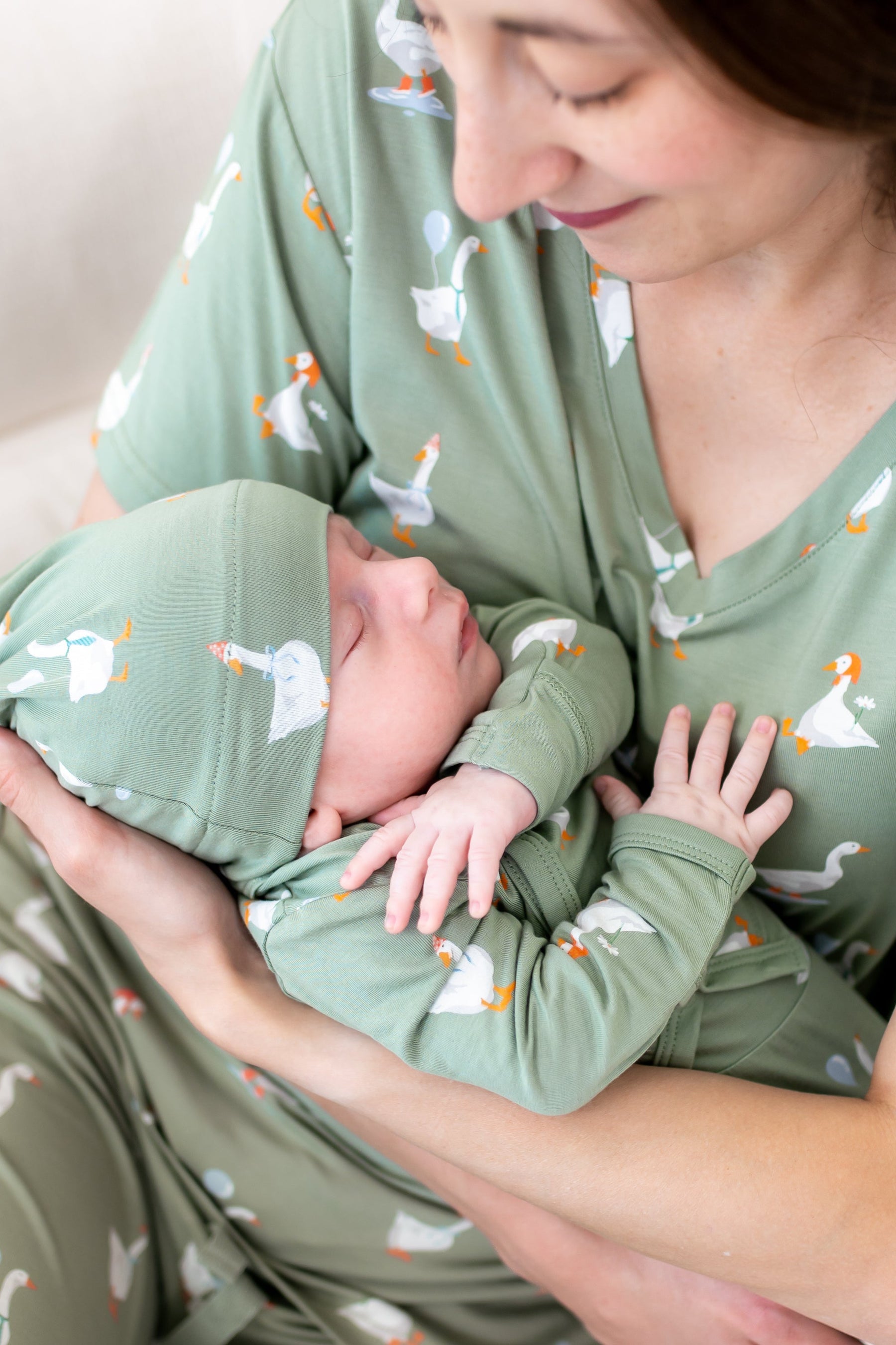 Close up of mother holding sleeping newborn wearing the Take Me Home Set in Silly Goose