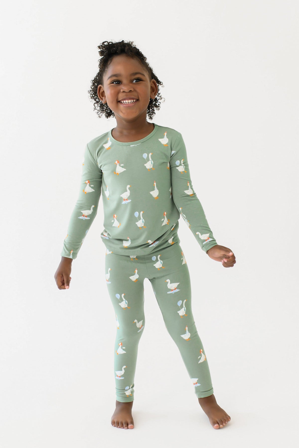 smiling girl standing with her arms out wearing the Long Sleeve Pajamas in Silly Goose in front of a white backdrop