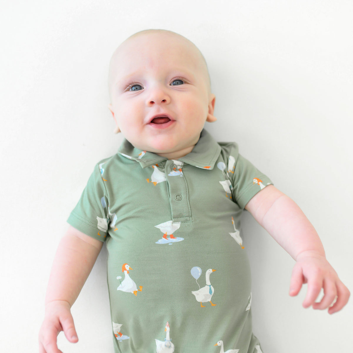 Close up of the button placket and collared neckline of the Polo Shortall in Silly Goose on an infant model 
