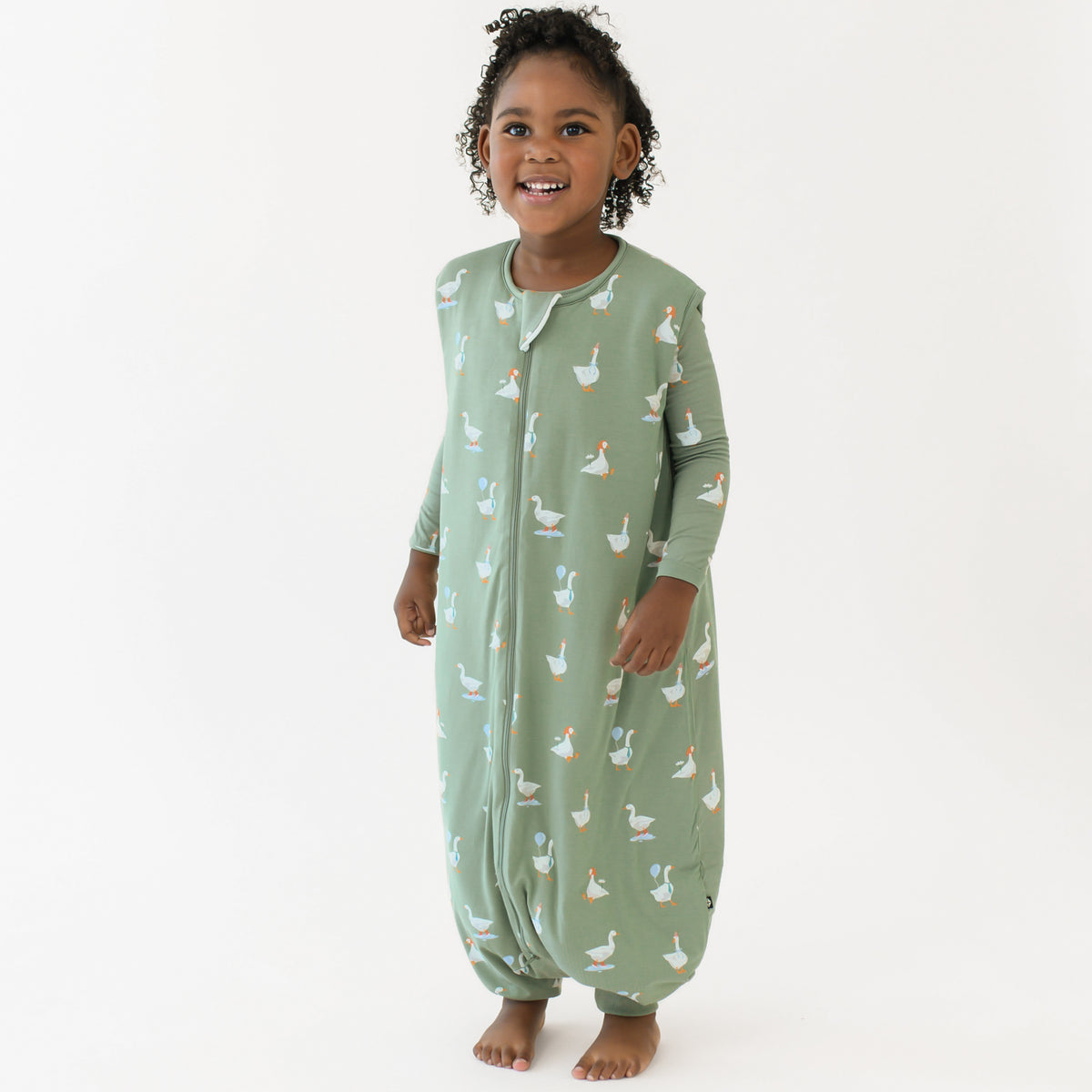 Young girl standing wearing the Sleep Bag Walker in Silly Goose 1.0 with matching long sleeve toddler pajamas on underneath