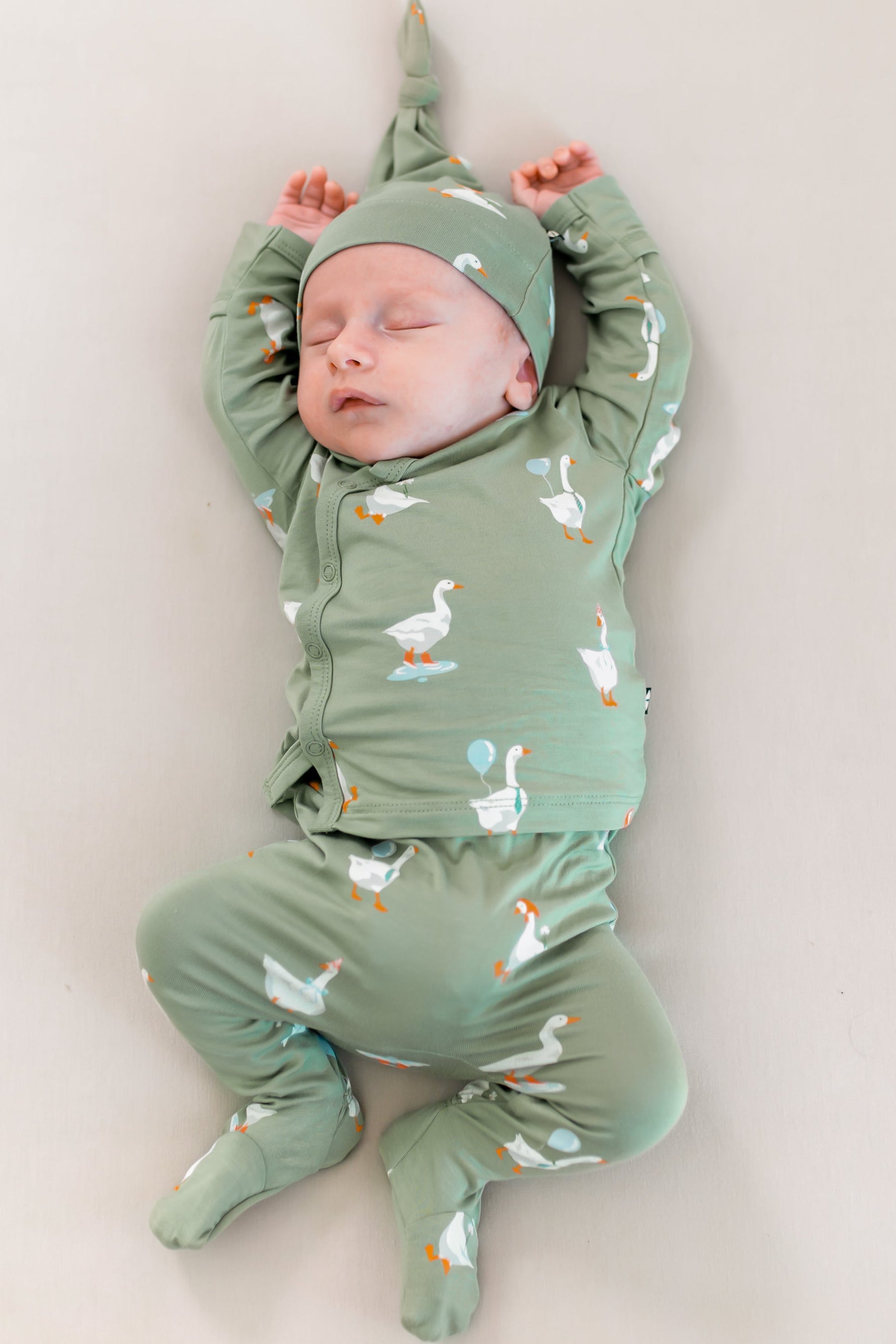 Sleeping newborn laying down with arms above their head wearing the Take Me Home Set in Silly Goose