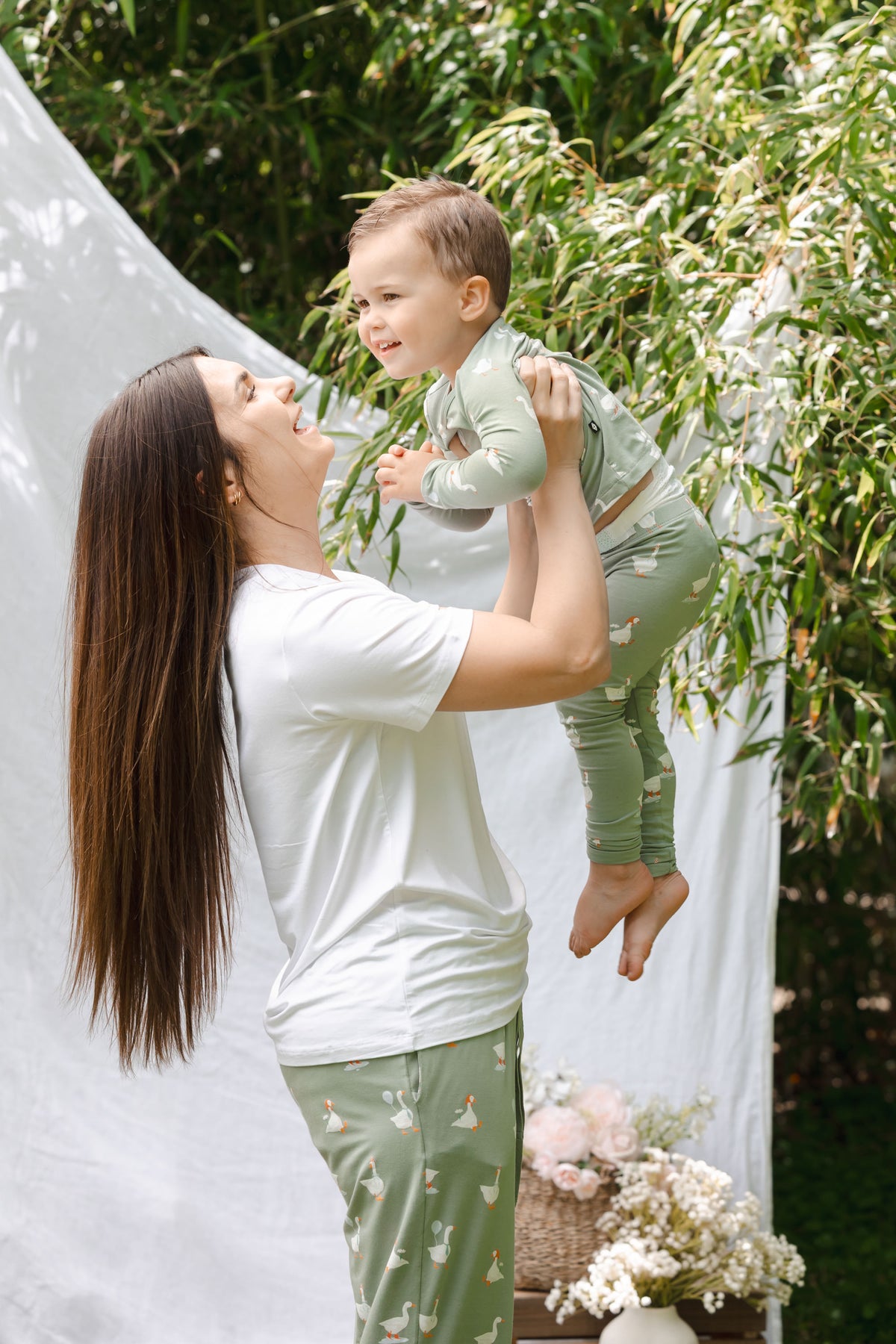 Mom holding up toddler wearing silly goose pajamas outdoors