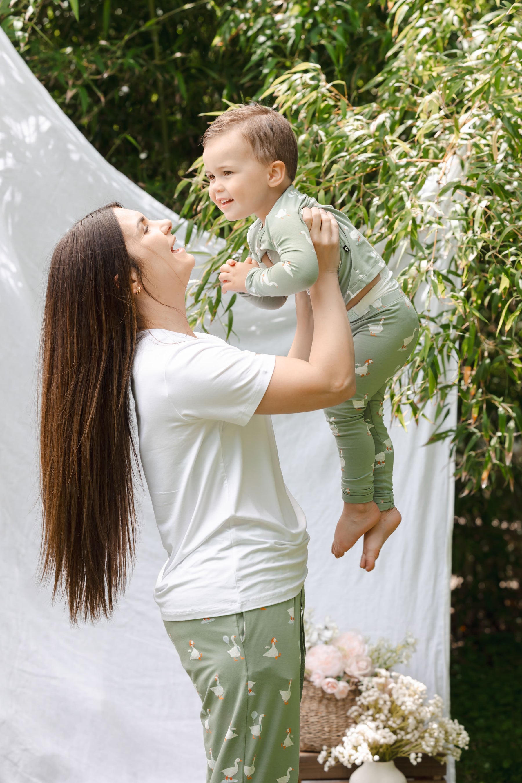 Mom holding up toddler wearing silly goose pajamas outdoors
