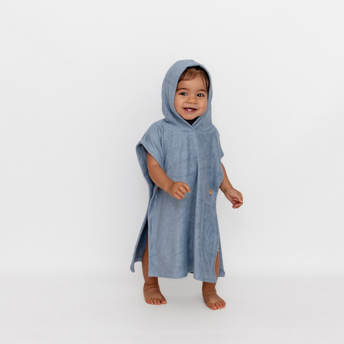 Young girl walking wearing the Swim Poncho in Slate with the hood up 