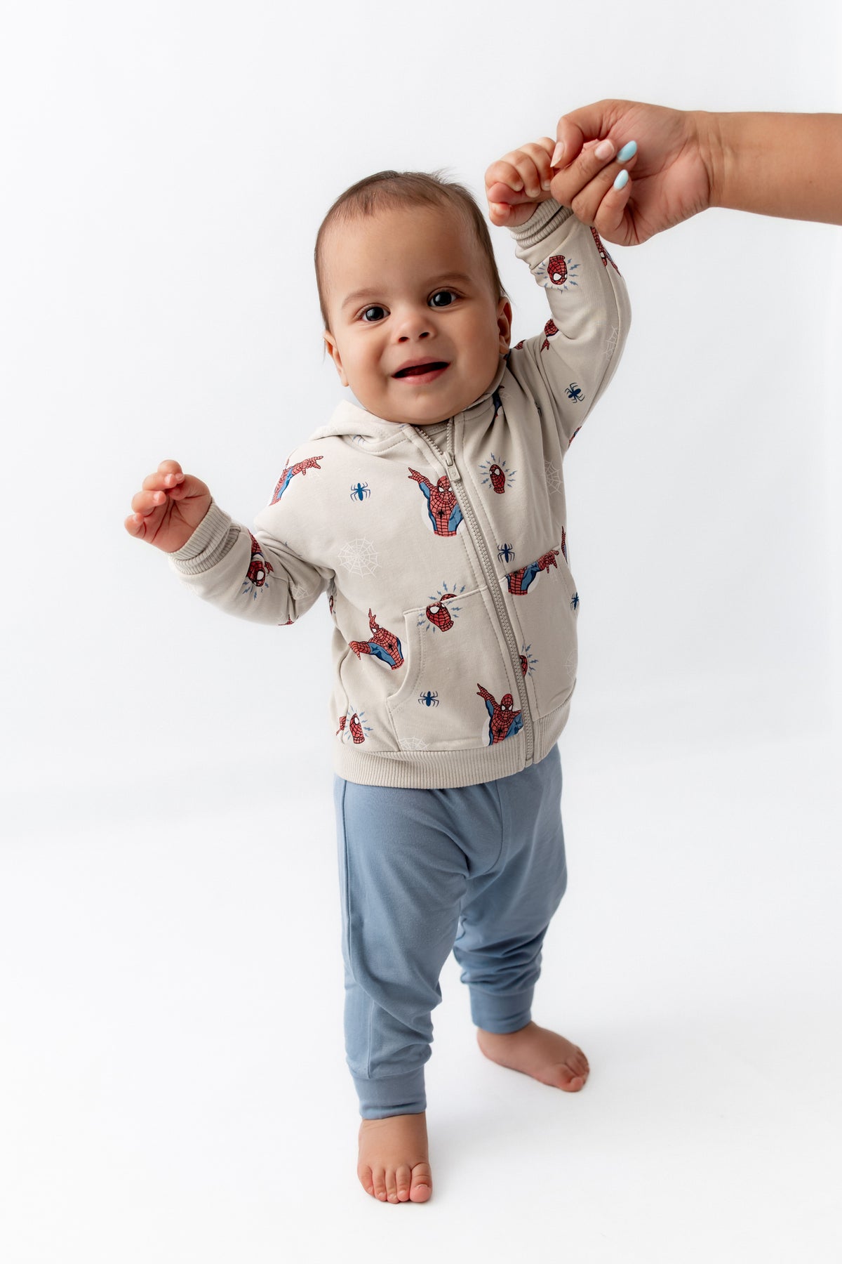 Toddler standing smiling in a zippered jacket in spiderman.