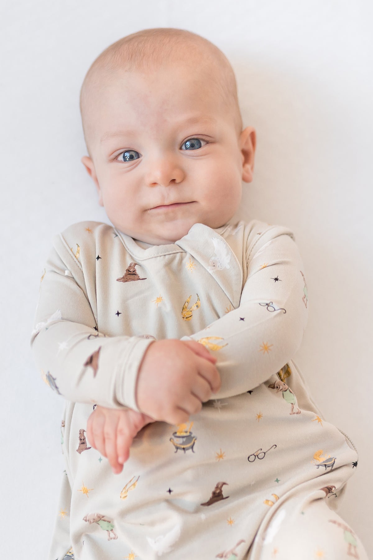 Baby in a sleep bag with Harry Potter prints on a white background