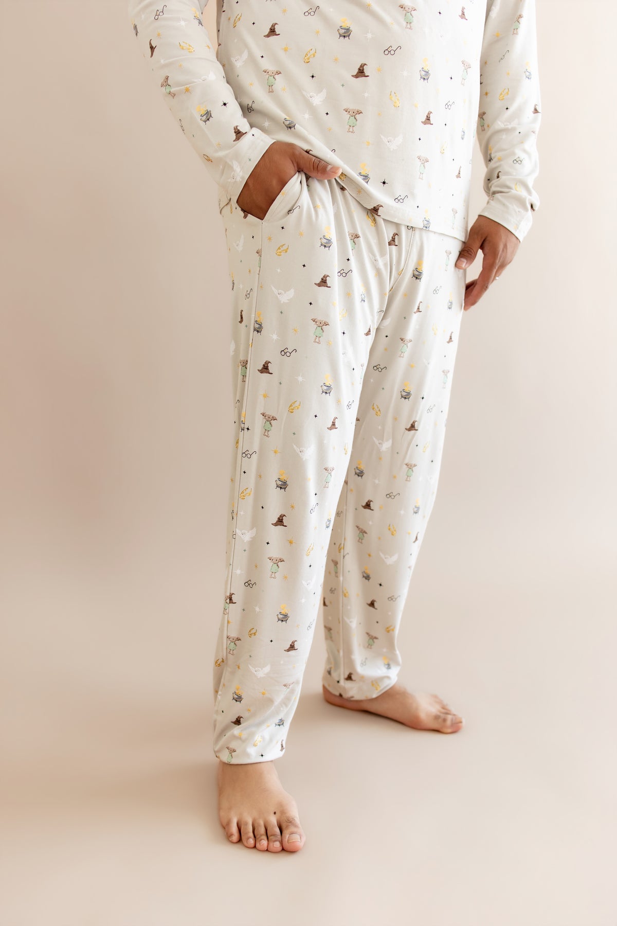 Person wearing men's jogger set pajama with pocket having Harry Potter prints on cream fabric