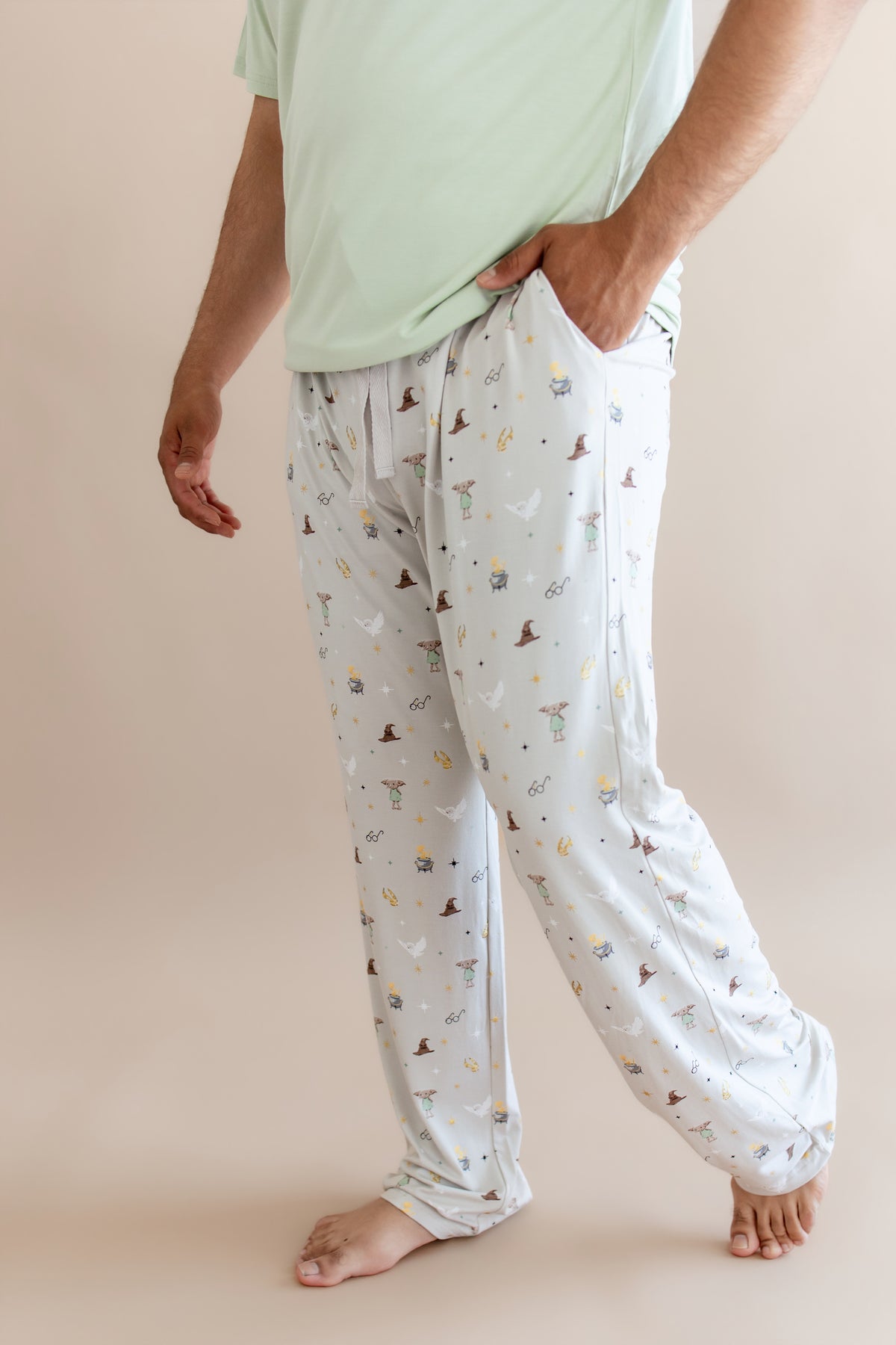 Person wearing a cream men's lounge pant with pocket having Harry Potter prints on a beige background