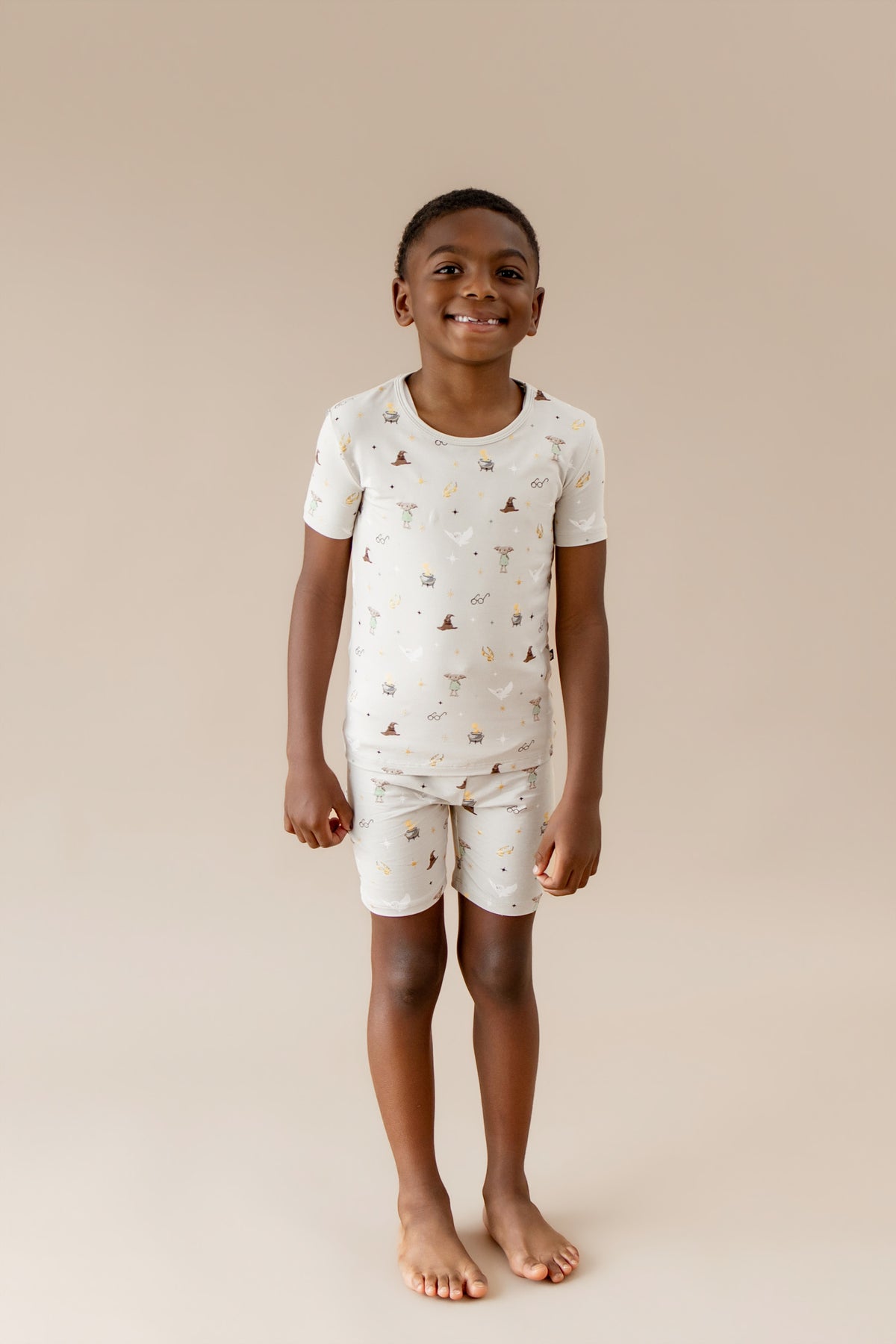 Child wearing a cream Harry Potter patterned short pajama set on a beige background