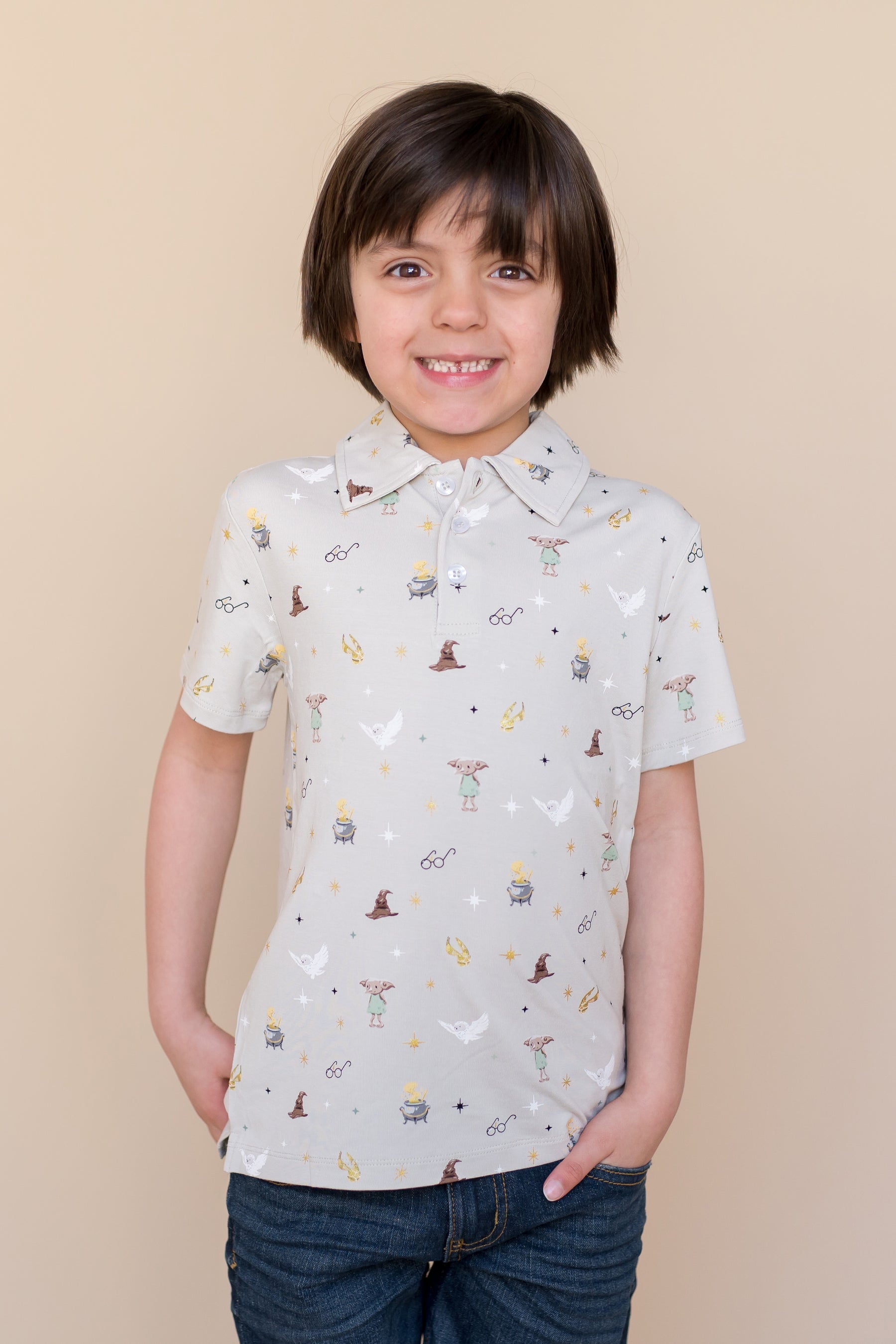 Child wearing a short-sleeve polo shirt with Harry Potter prints on a beige background