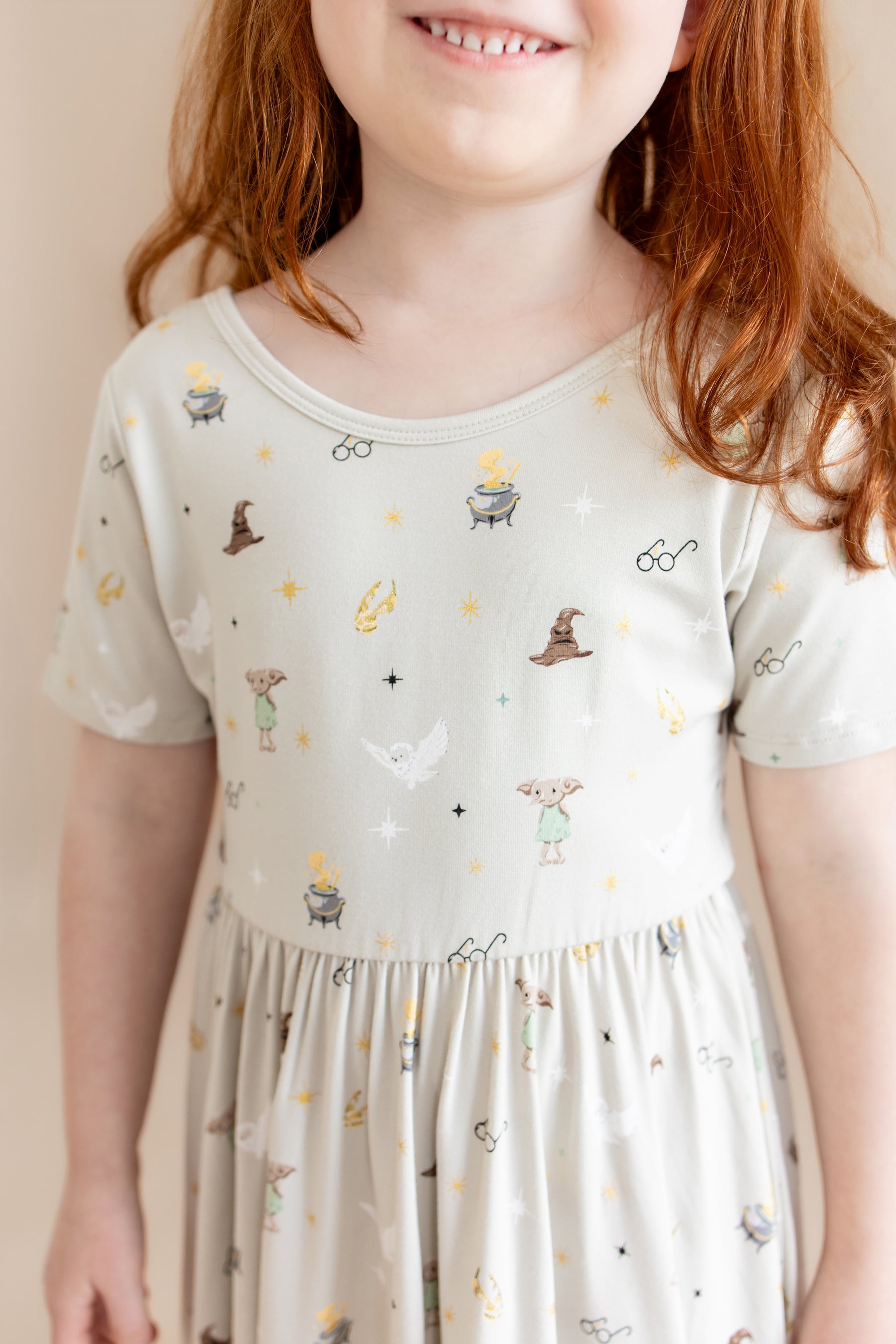Child wearing a cream Twirl dress with Harry Potter prints on a beige background