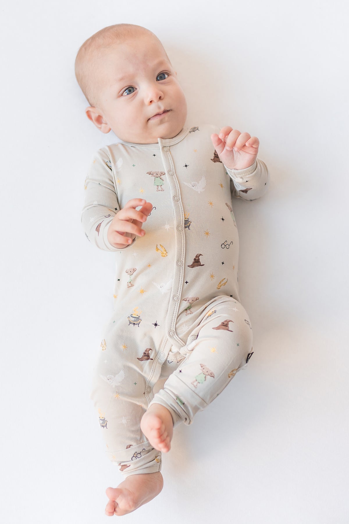 Baby wearing a cream snap romper with Harry Potter prints on a white background