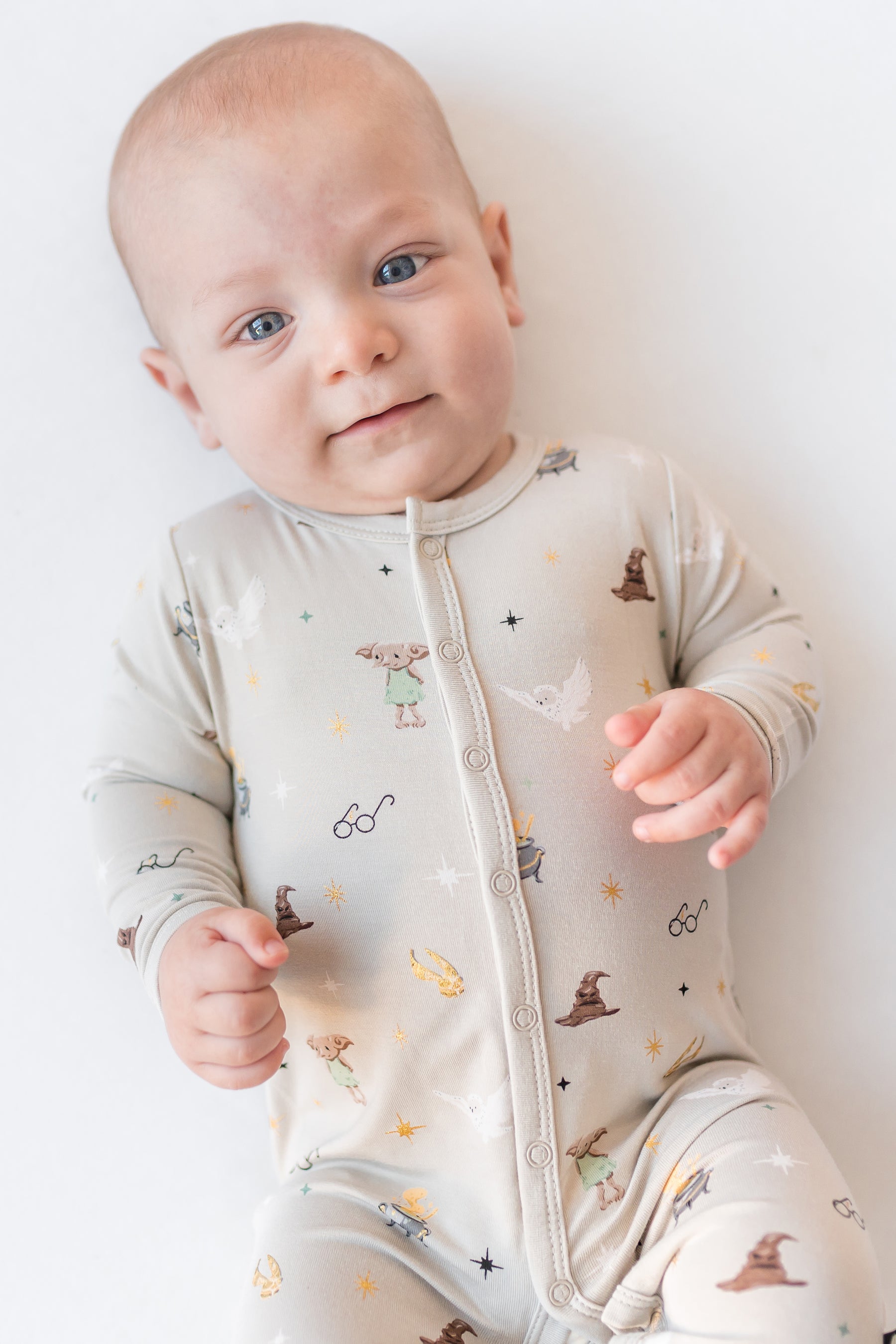 Baby wearing a Harry Potter patterned cream snap romper on a white background