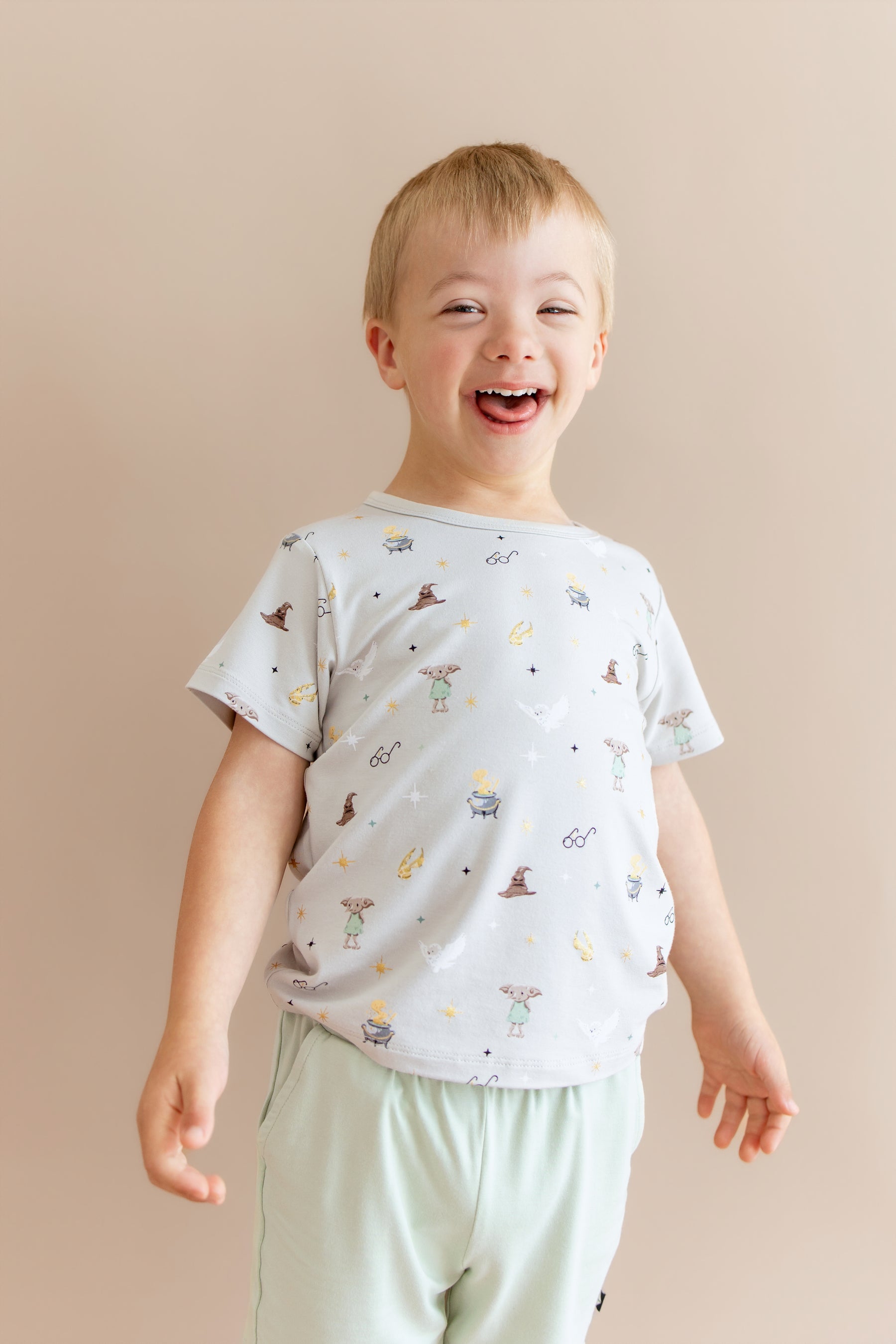Child wearing a Harry Potter patterned Toddler Basic Tee with green shorts on a beige background 