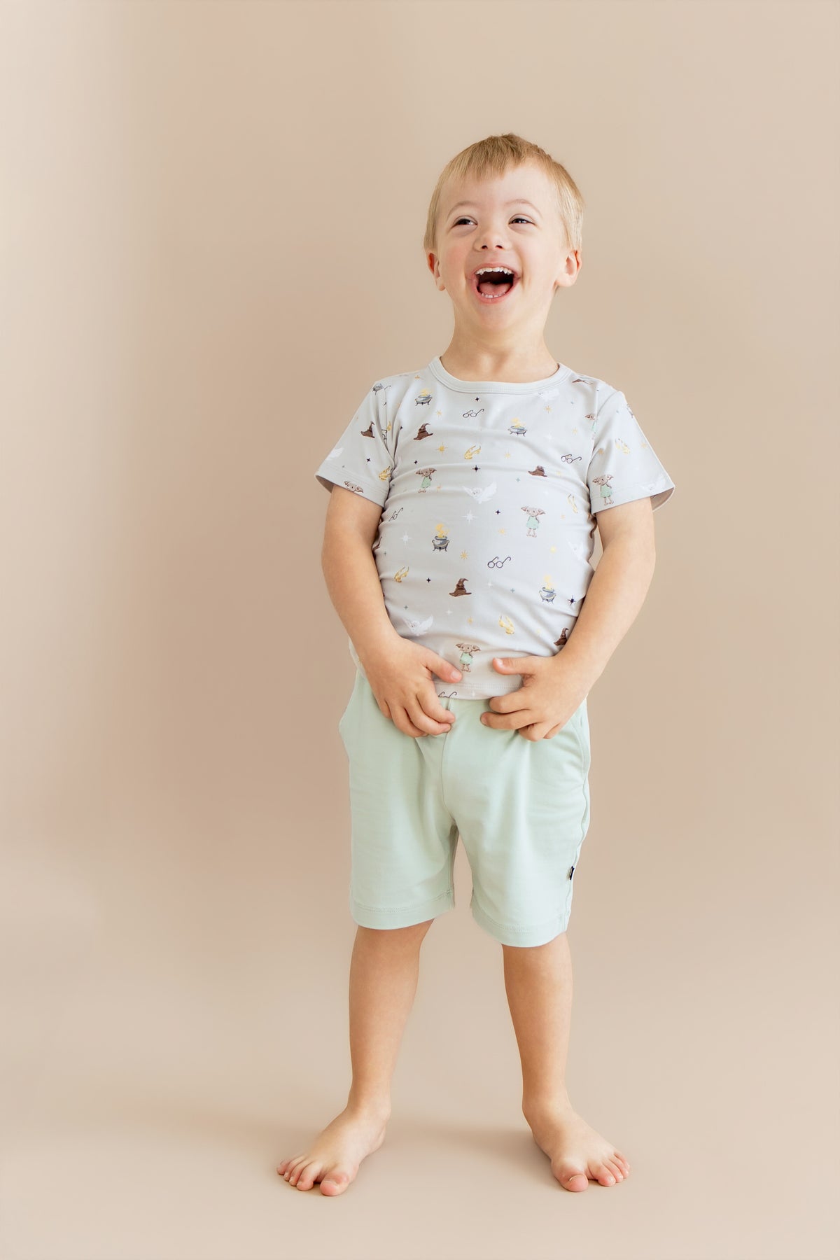 Child wearing a Harry Potter patterned Toddler Basic Tee with green shorts on a beige background