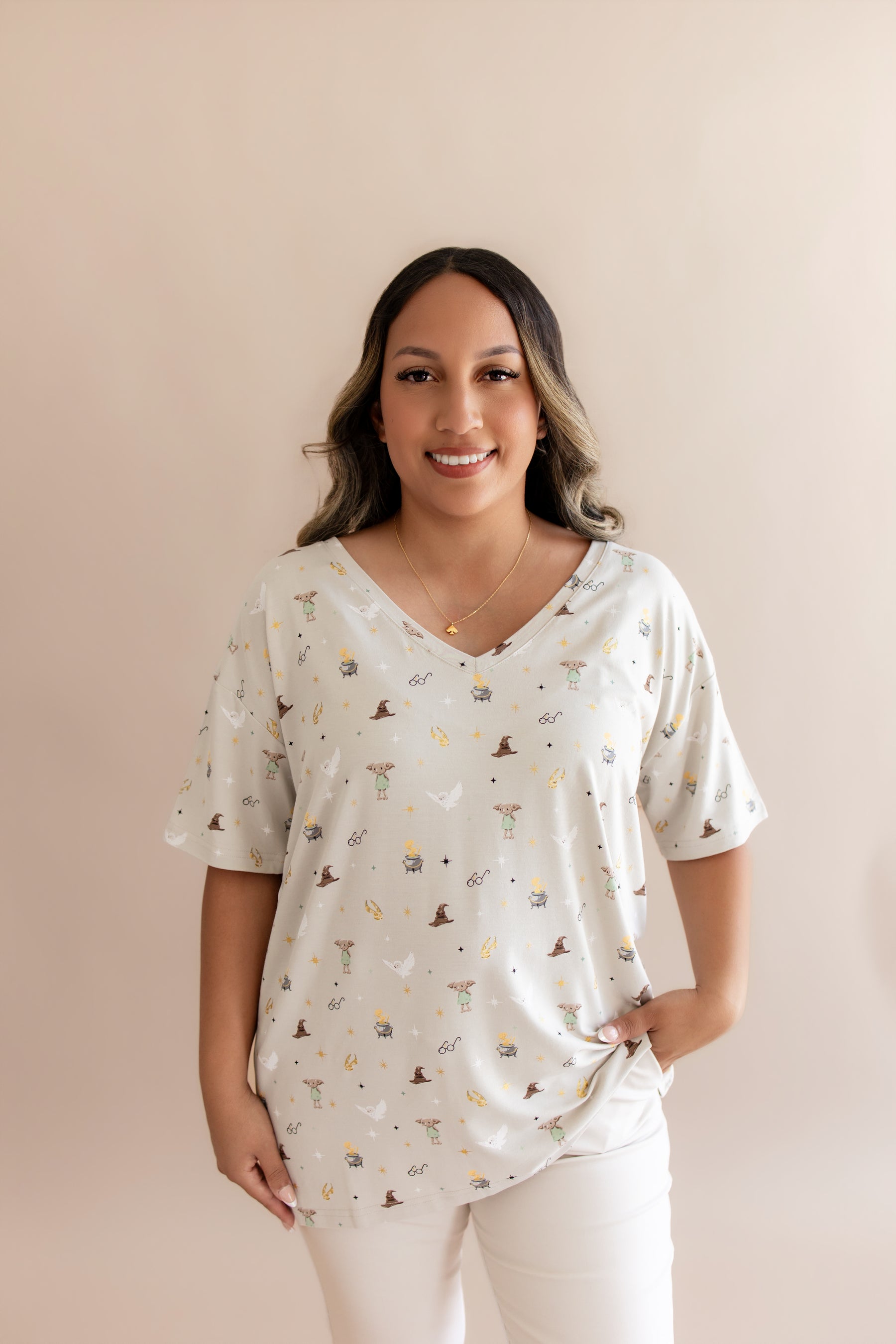 Model wearing a cream Women's Relaxed Fit V-Neck with Harry Potter prints with cream pants on a beige background