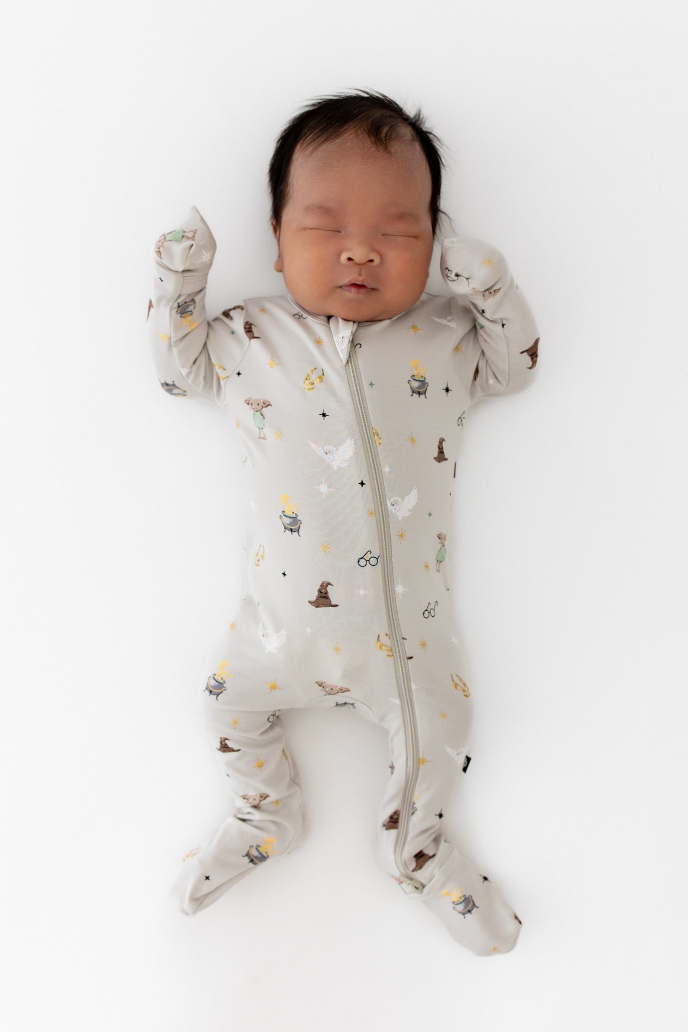 Baby wearing a cream Zippered Footie with Harry Potter prints on a white background