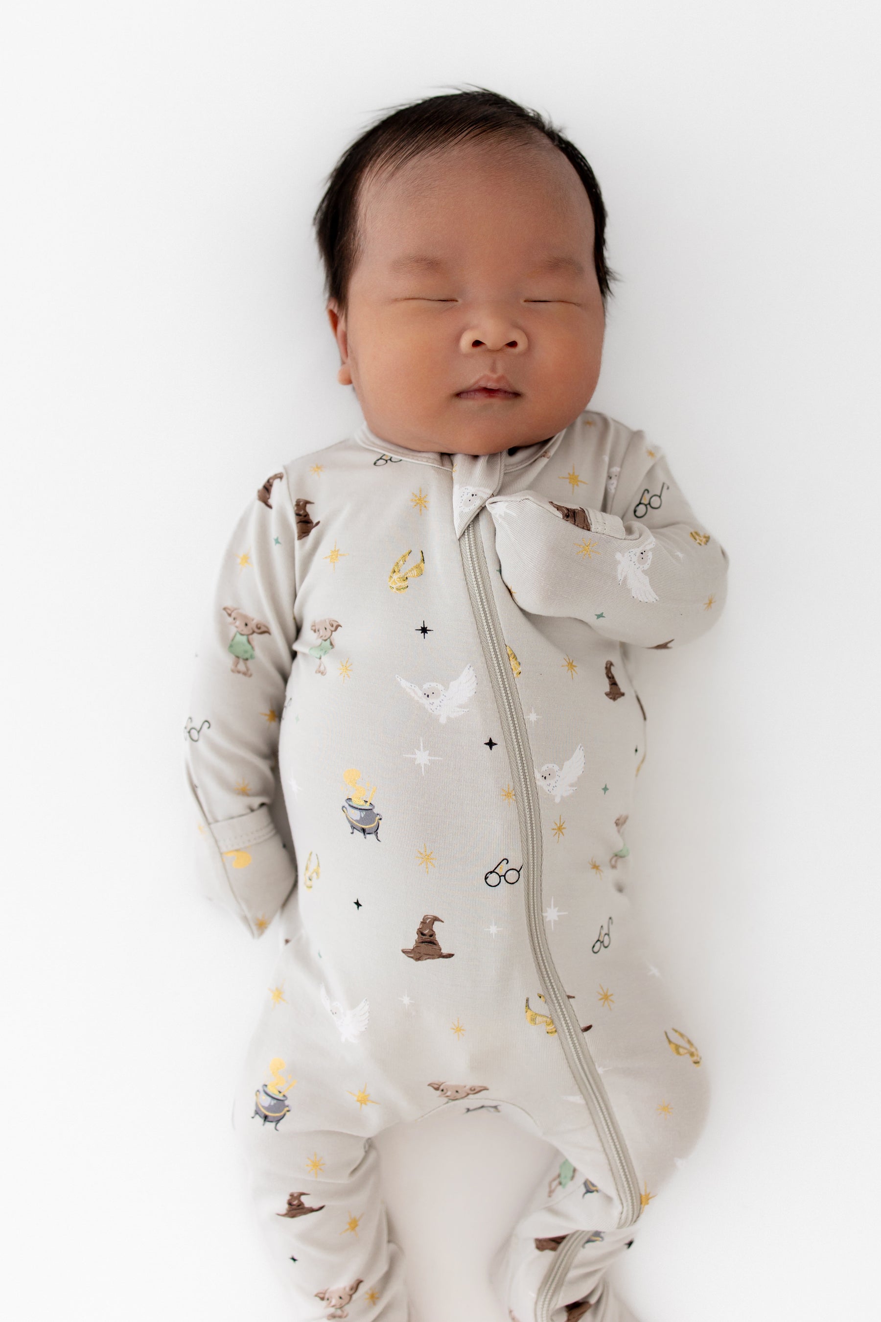 Baby wearing a cream Zippered Footie with Harry Potter prints on a white background