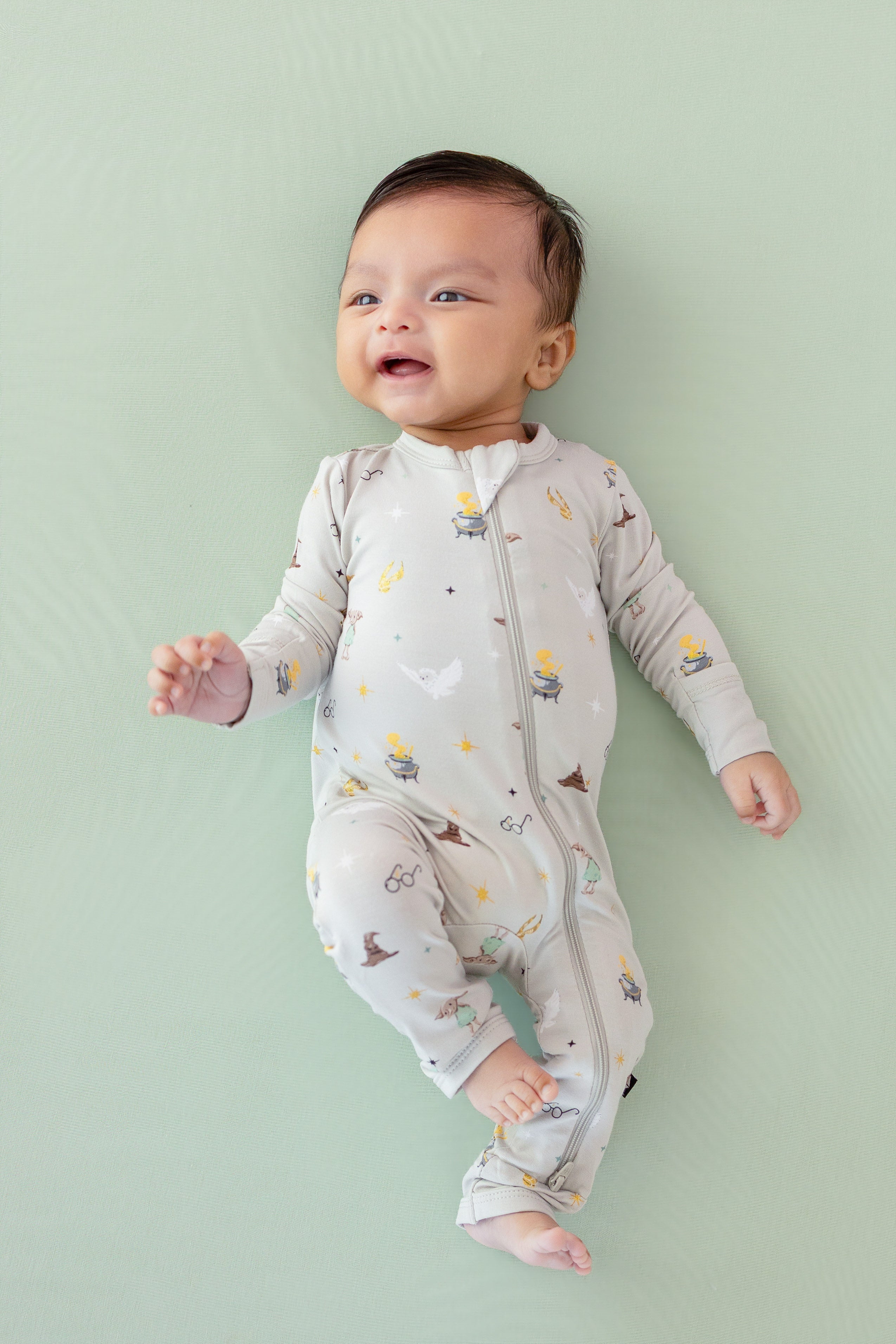 Baby wearing a Harry Potter patterned Zippered Romper on a green background
