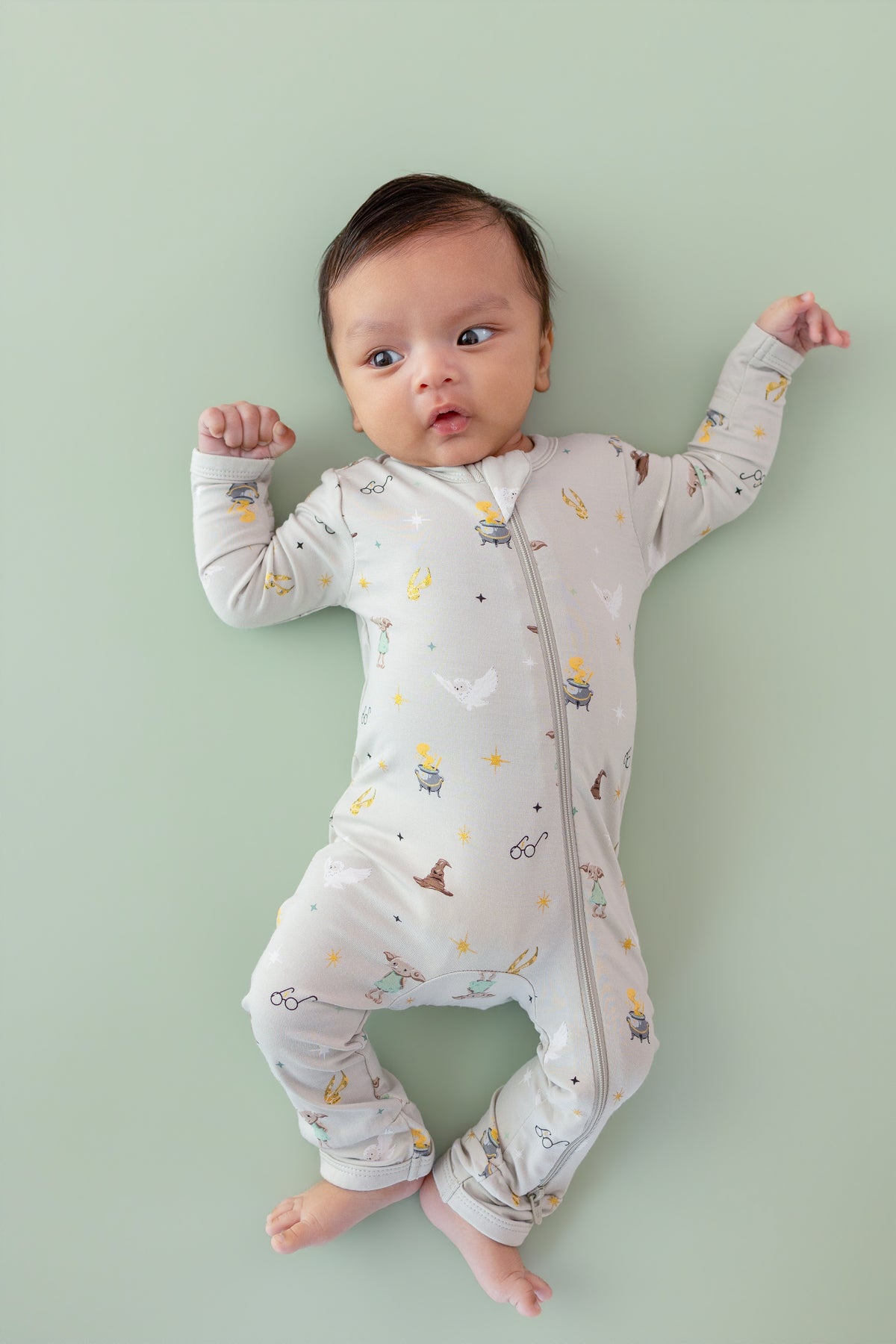 Baby wearing a Harry Potter patterned Zippered Romper on a green background