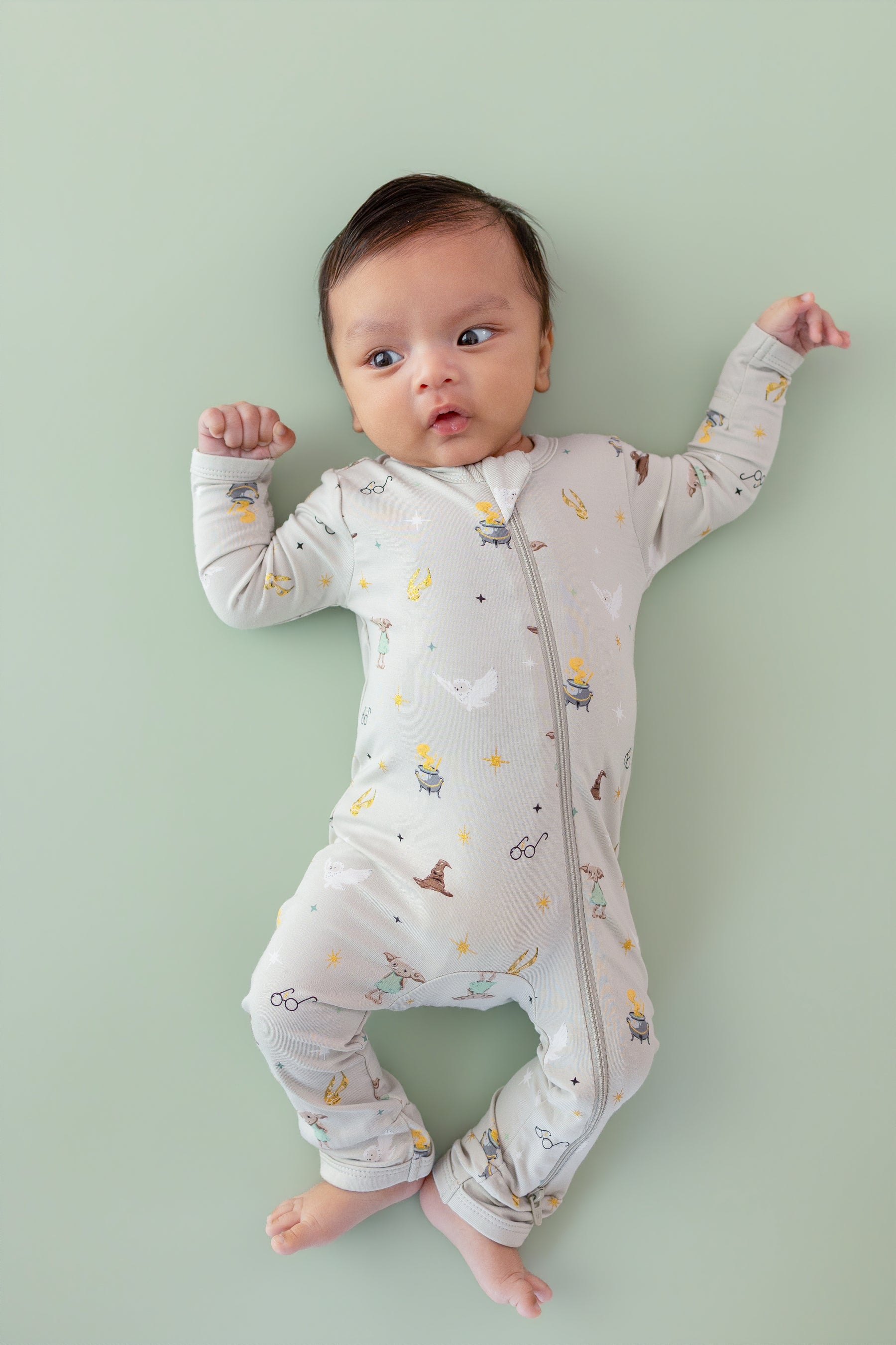 Baby wearing a Harry Potter patterned Zippered Romper on a green background