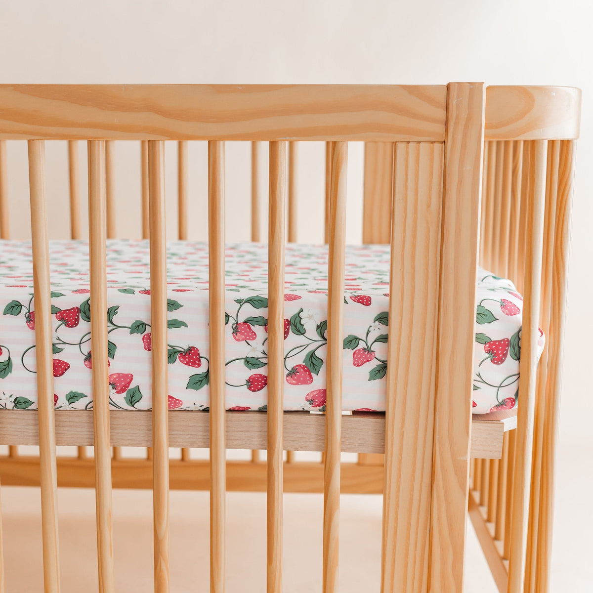Crib Sheet in Strawberry Fields shown on a crib mattress in a wooden crib