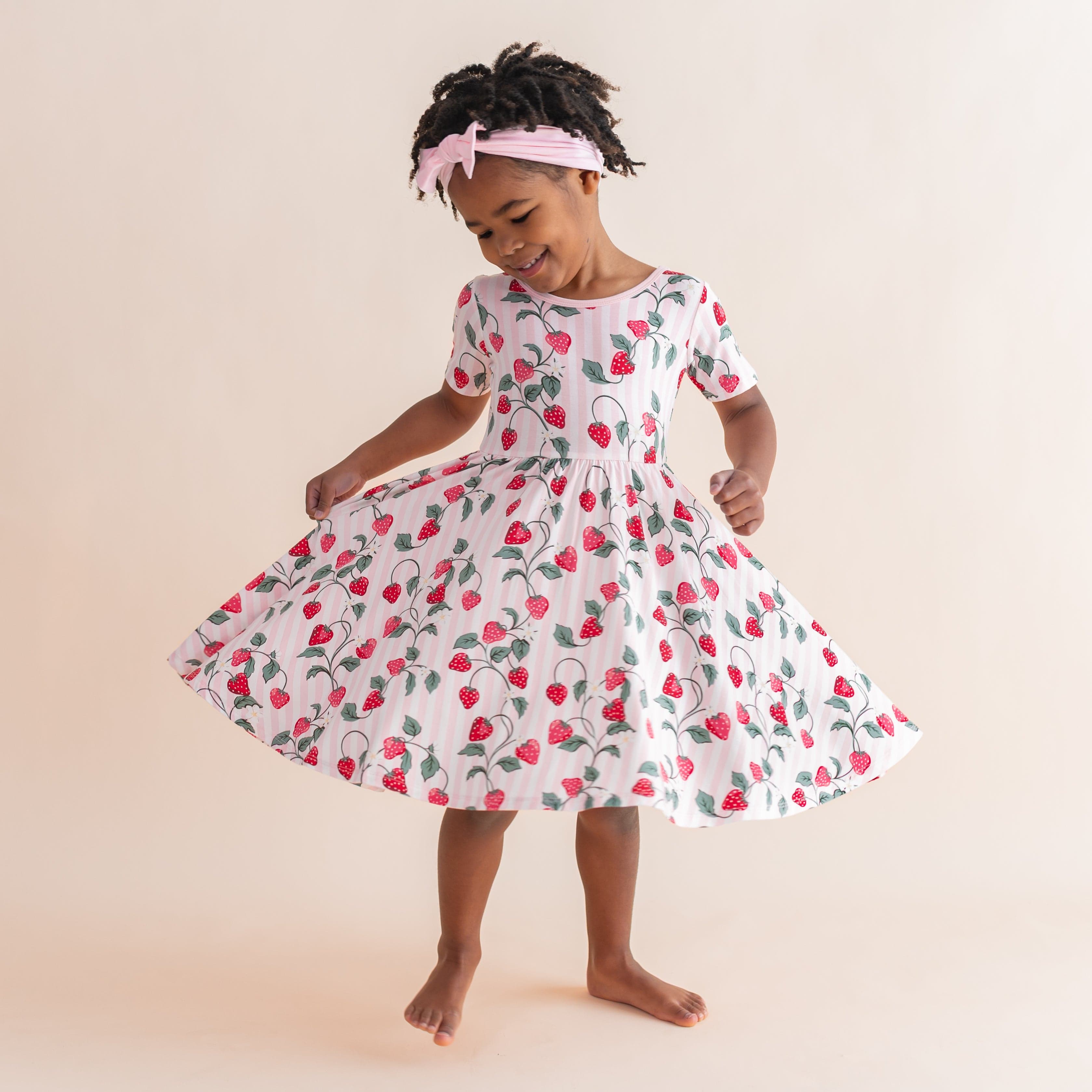 Young girl twirling in the light and airy Twirl Dress in Strawberry Fields