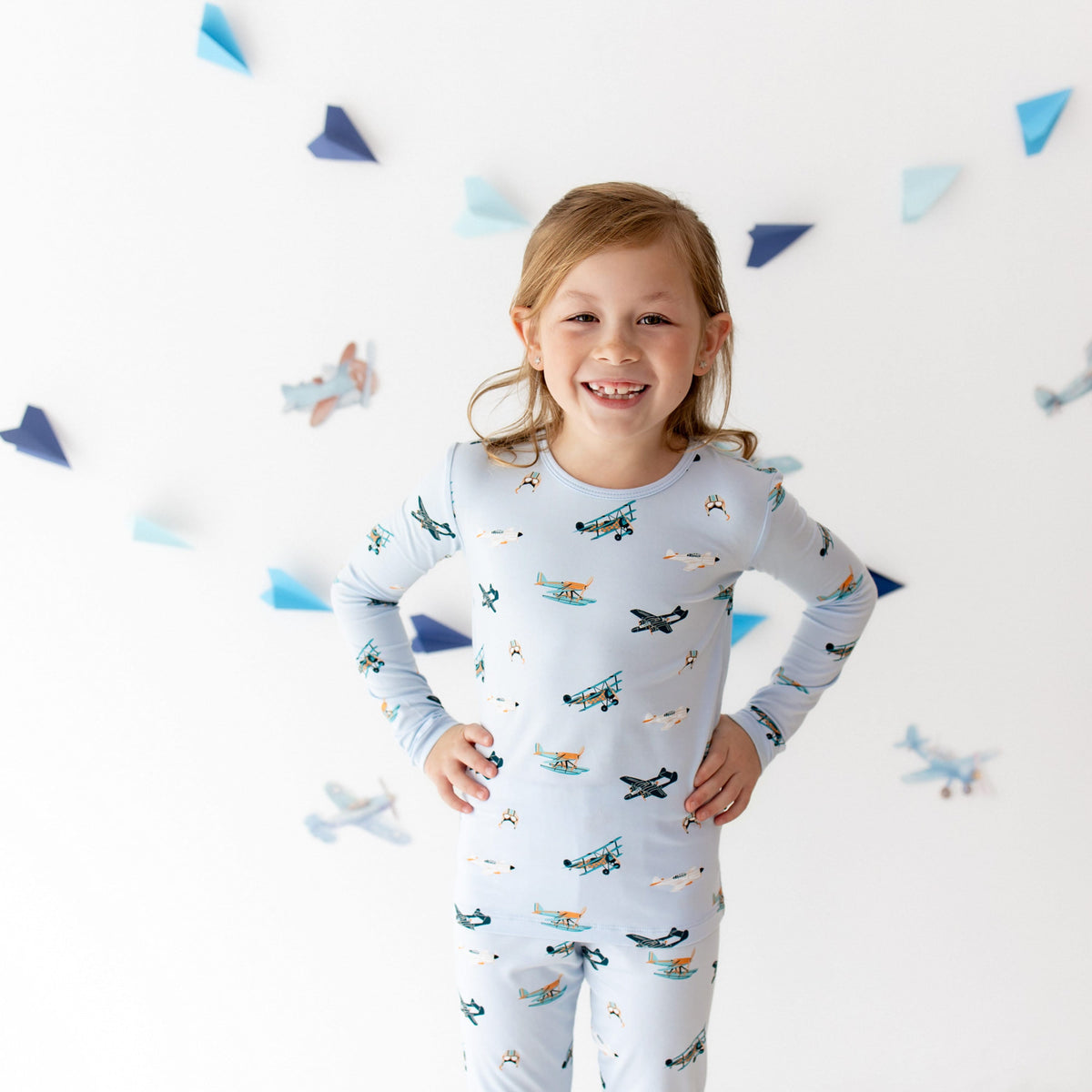 Smiling girl standing with both hands on her hips wearing the Long Sleeve Pajamas in Take Off