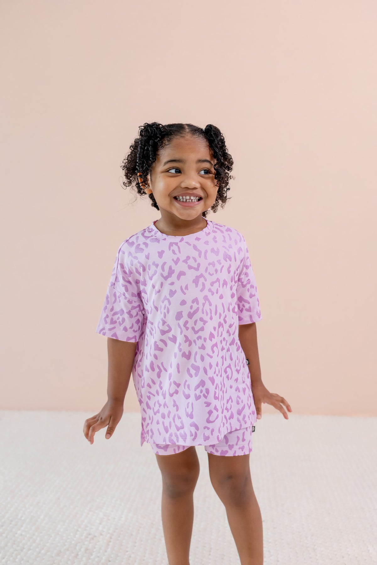 Child wearing Thistle Leopard print Toddler Biker Short set on a beige background