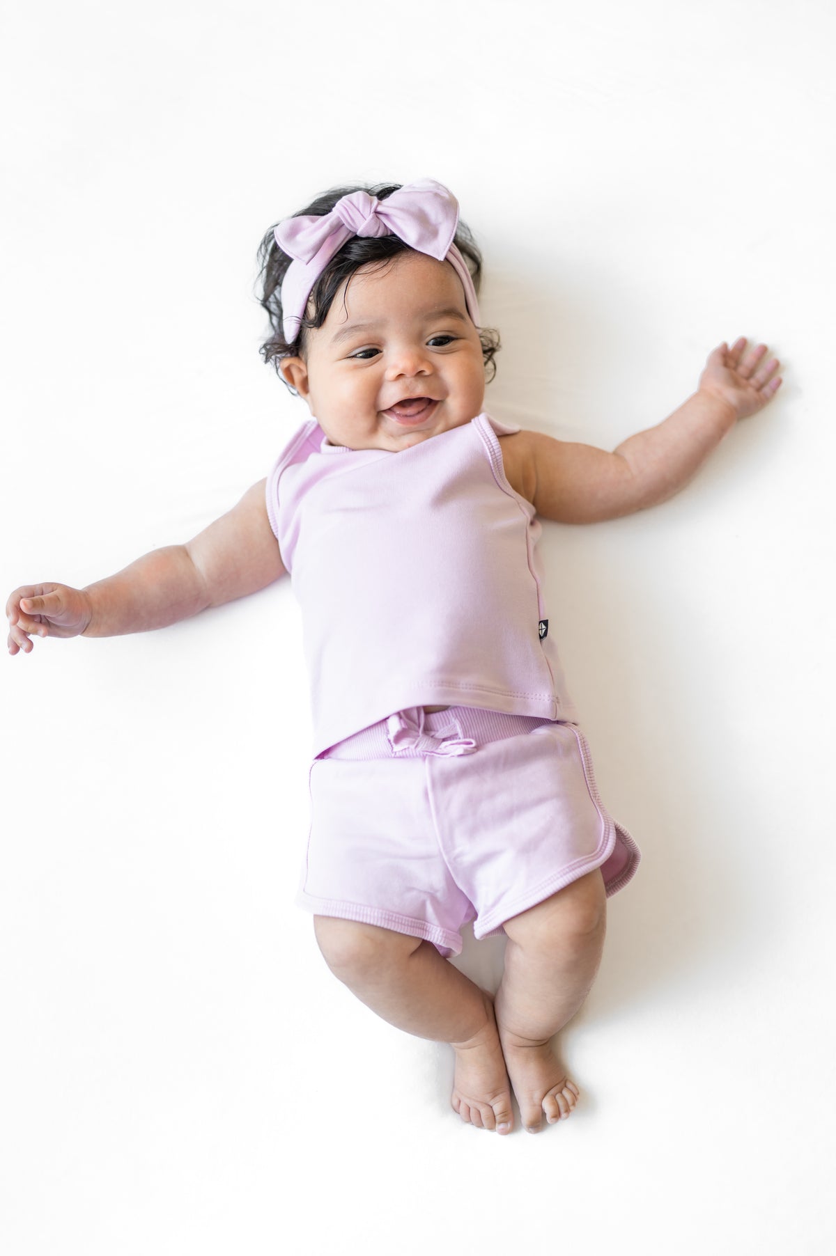 Young infant wearing the Tank Jogger Set in Thistle laying on a white surface