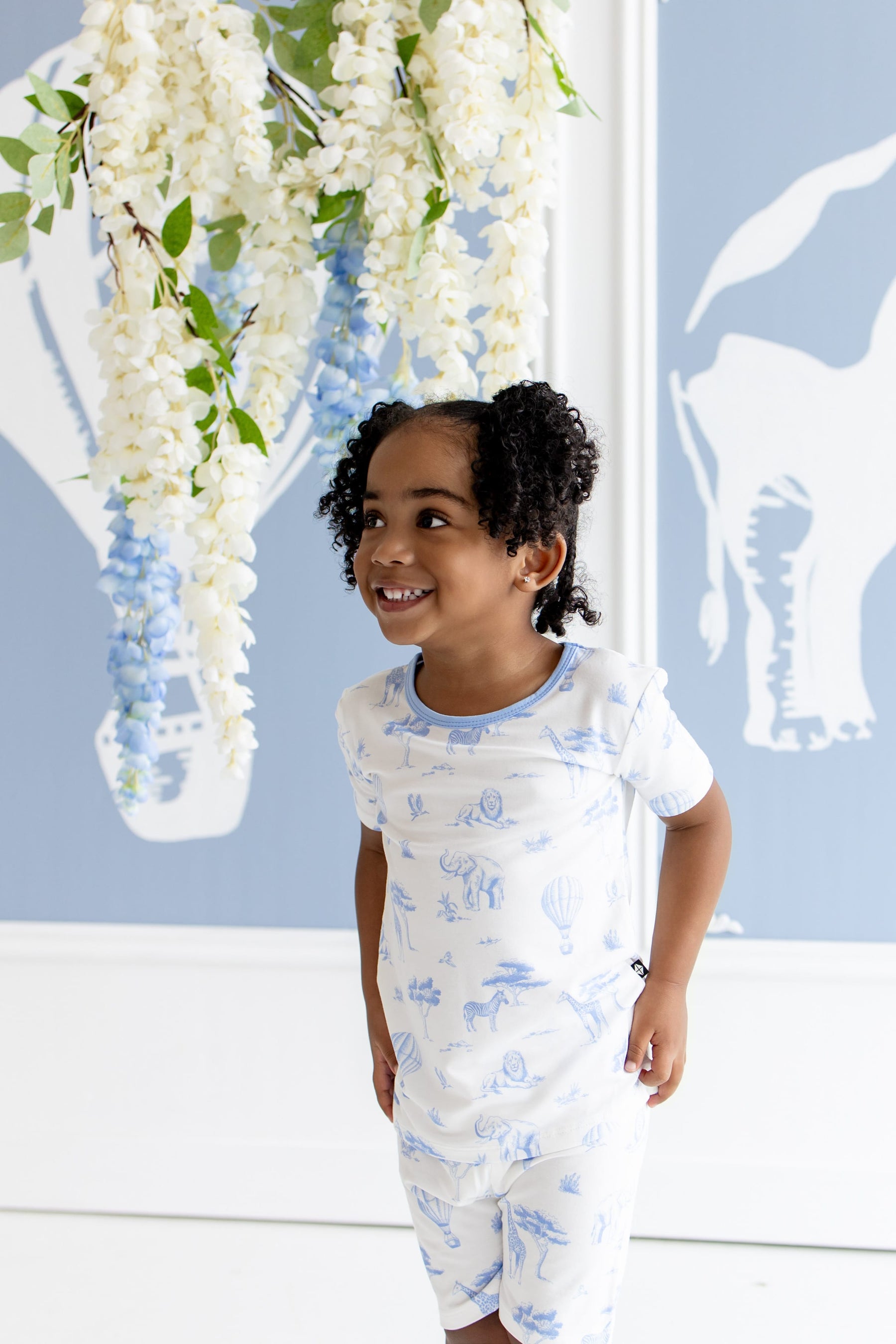Young girl looking off to the side modeling the Short Sleeve Pajamas in Toile Safari standing in front of a safari inspired backdrop