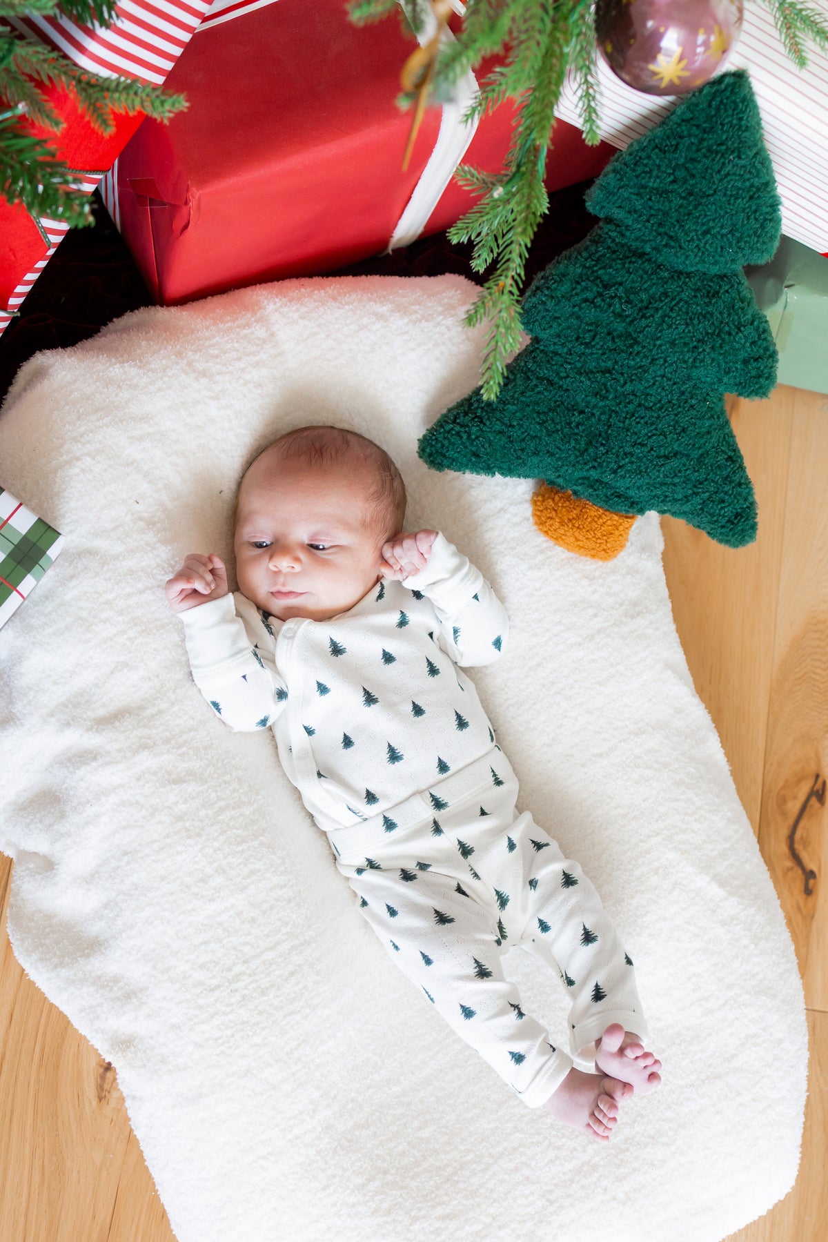 Baby wearing Pointelle Kimono Set in Christmas Trees lying on white sheet near Christmas tree