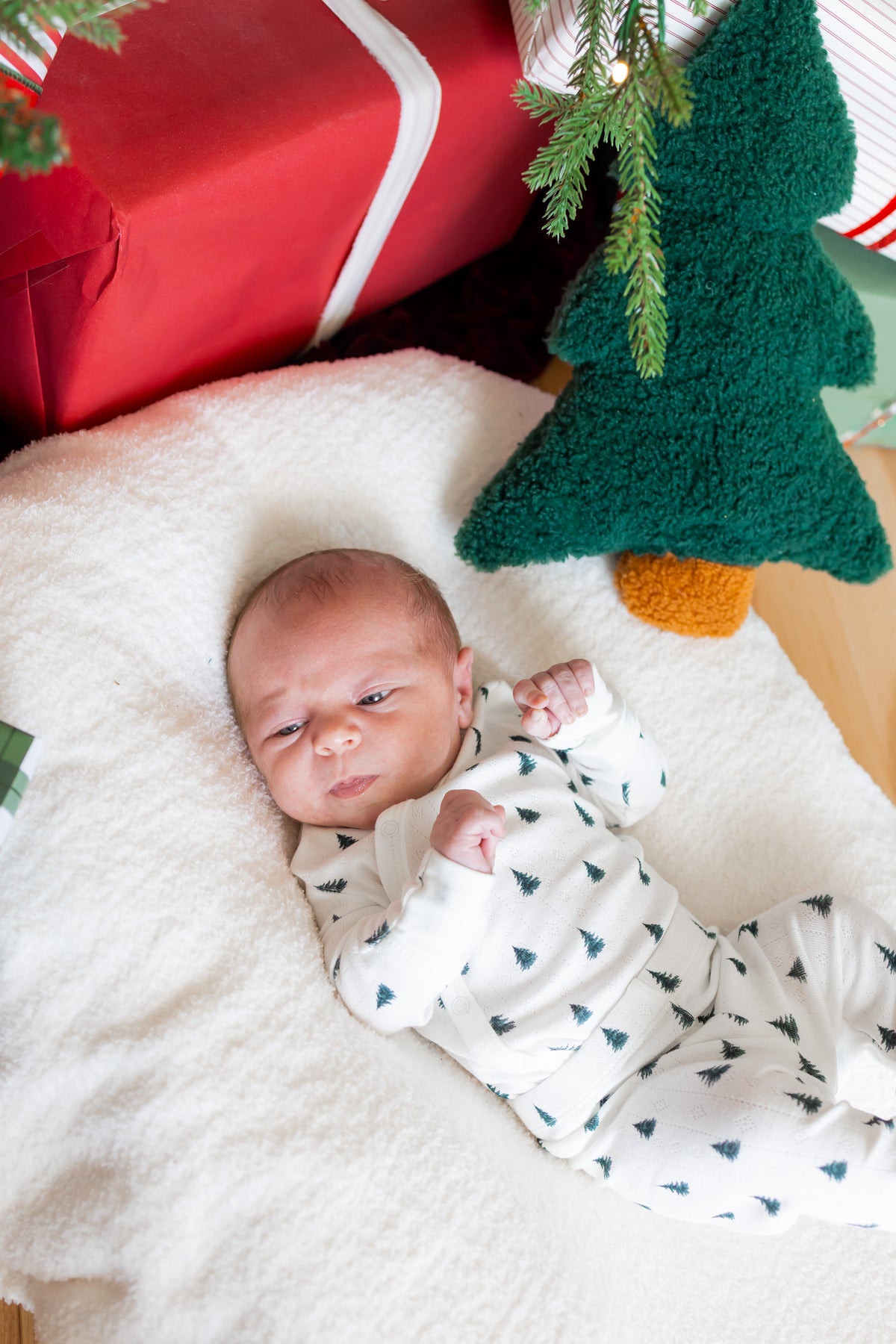 Baby wearing Pointelle Kimono Set in Christmas Trees lying on white sheet near Christmas tree