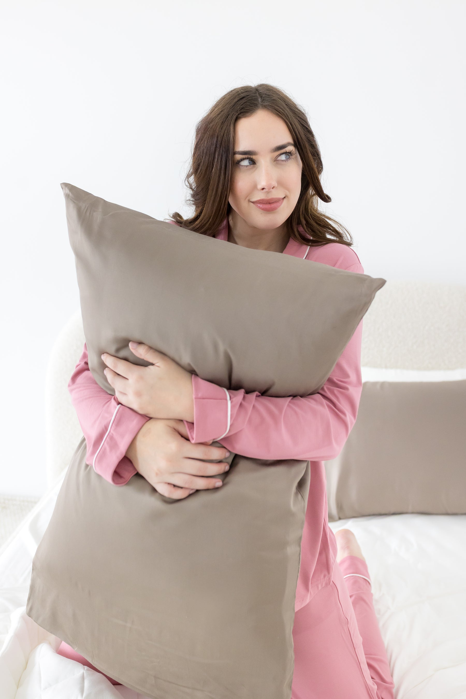 Female holding a pillow with the Bamboo Sateen Pillowcase in Truffle on it