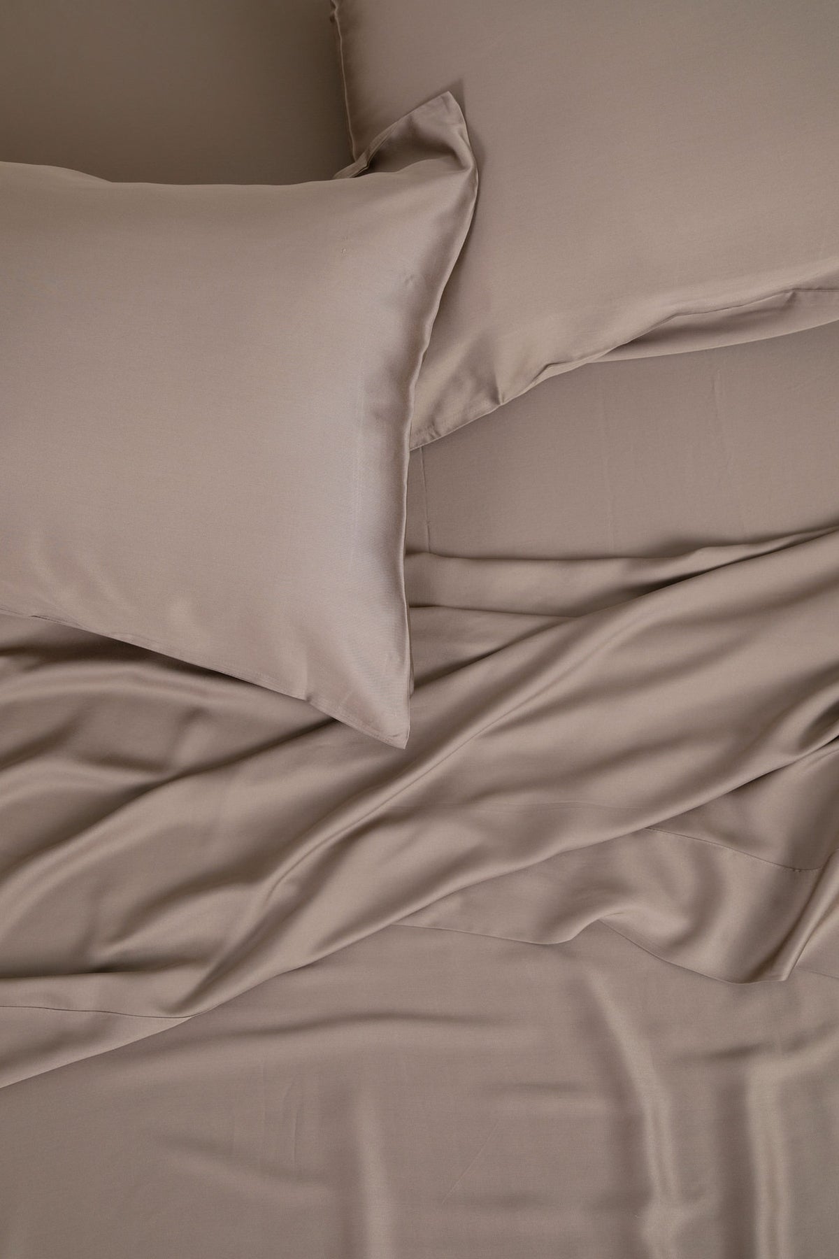 Close up of the Bamboo Sateen Pillowcase Set in Truffle with matching bed sheets on a bed