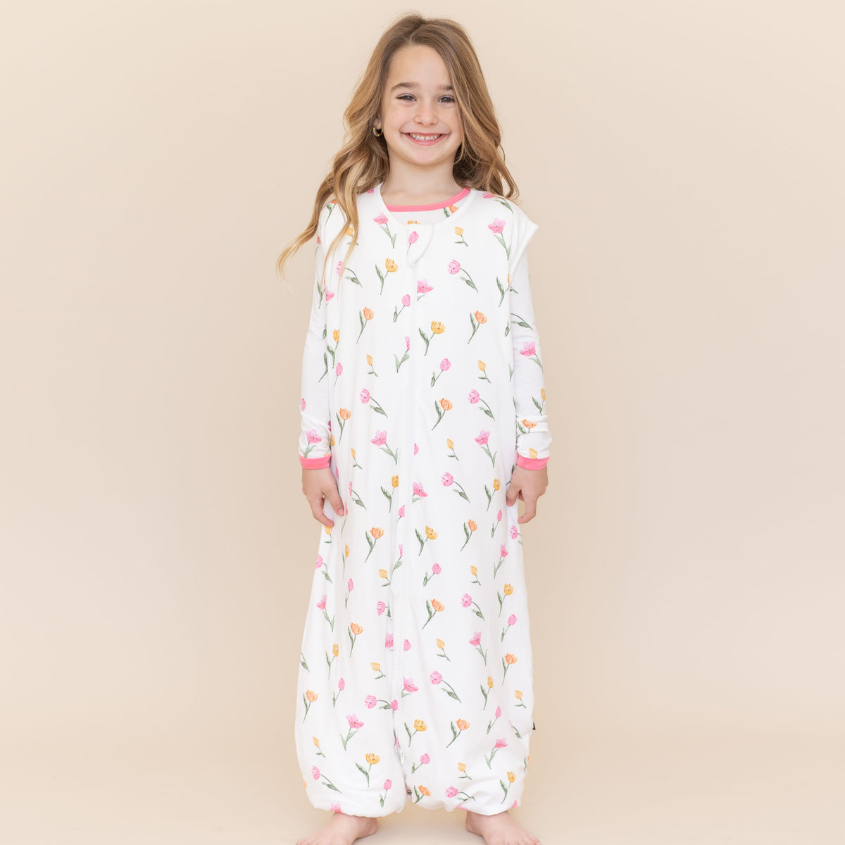 Young smiling girl modeling the Sleep Bag Walker in Tulip 1.0 with matching long sleeve pajamas on underneath