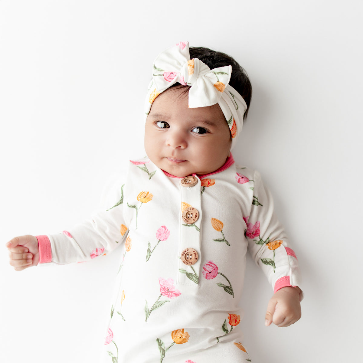 Close up of an infant wearing the Knotted Gown with Bow Set in Tulip